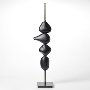 tall stacked sculptural light consisting of four abstract black shapes held on a long steel pole with a square base each with a LED light inside hand blown from glass with a textured cut surface