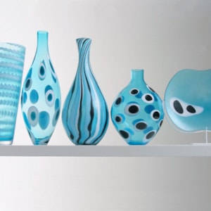 five glass vase sculptures of different sizes in aqua blue