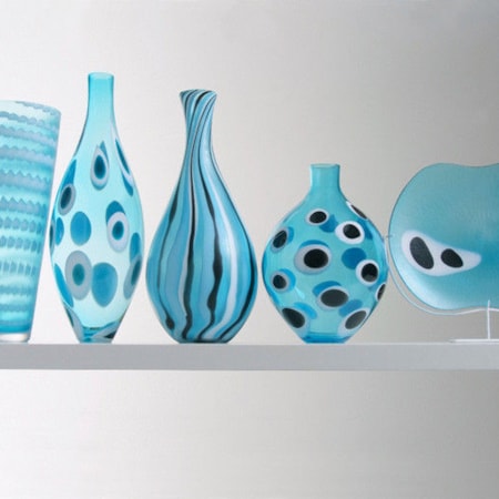five glass vase sculptures of different sizes in aqua blue