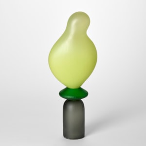 tall opaque abstract figurative sculpture created in three sections starting with a bottom grey stemless upside down goblet shape then a round disc in apple green topped with the bright light lime undulating balloon form hand made from blown glass with a repeat cut textured surface