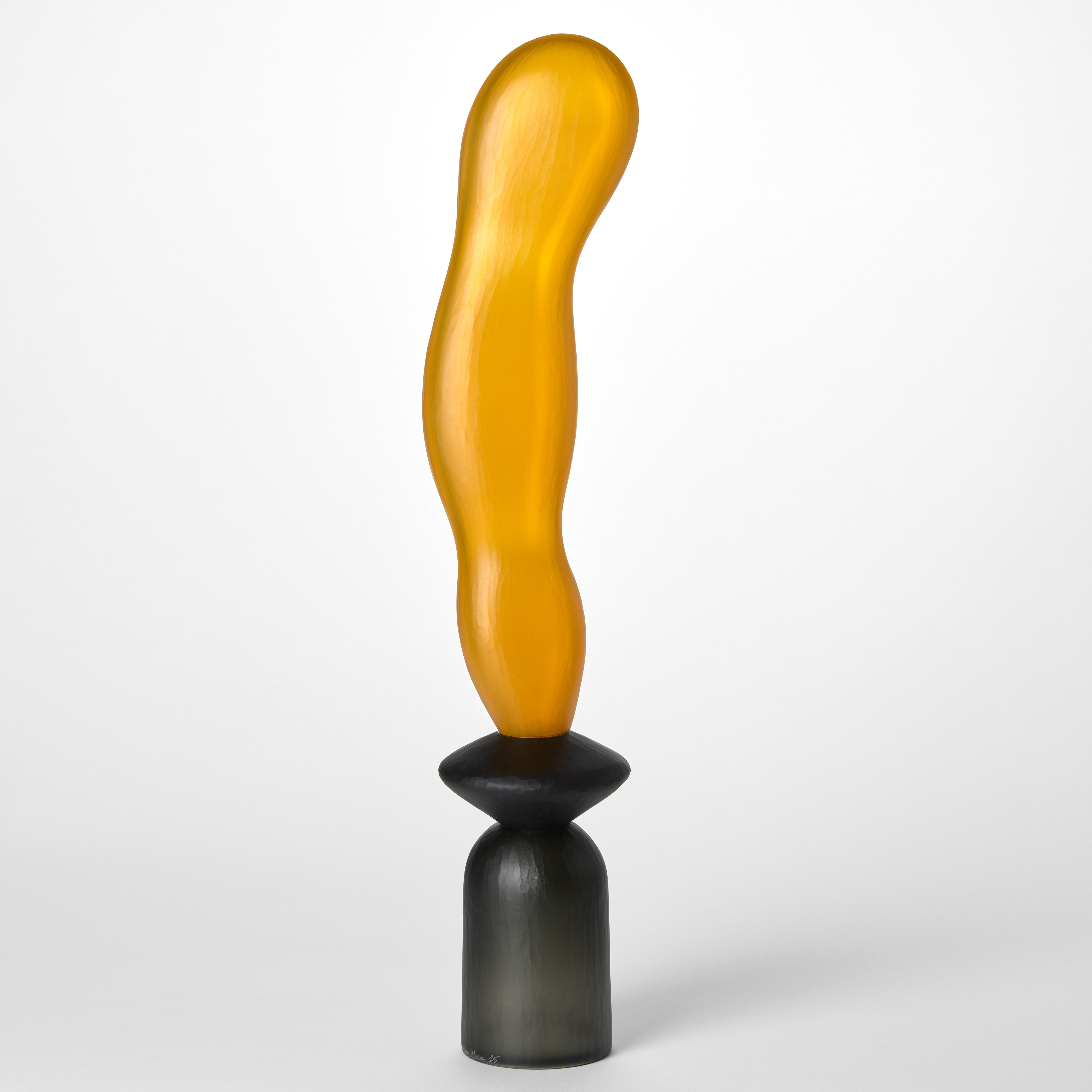 tall opaque abstract sculpture created from three balanced forms one on top of the other starting with an upside down grey cup then a disc in black with a long extended orange undulating balloon form on top hand made from blown glass with a textured surface