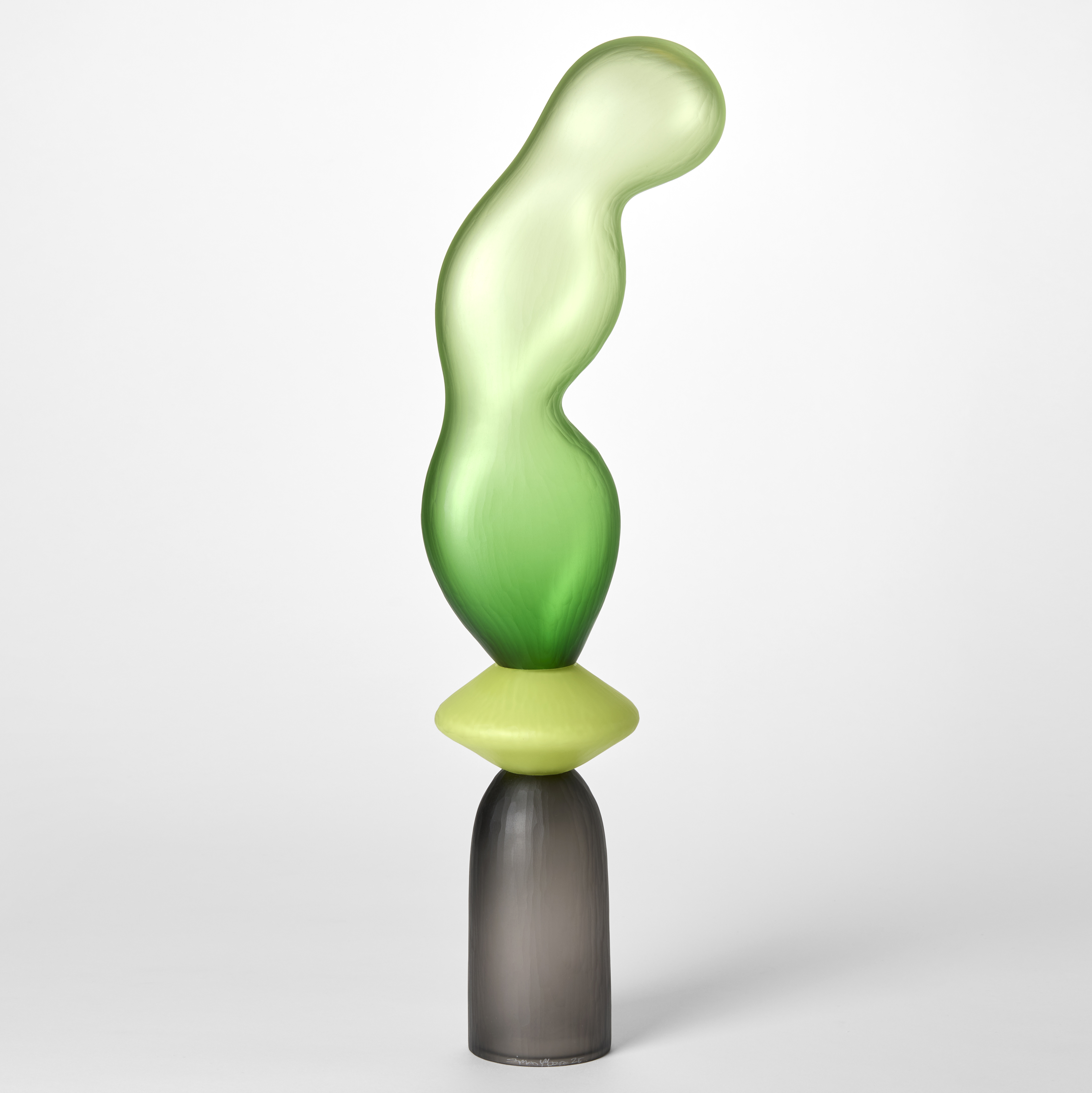 tall opaque sculpture consisting of three stacked forms a grey cup a lime yellow disc and an undulating bulbous balloon in green hand made from blown glass with a textured surface