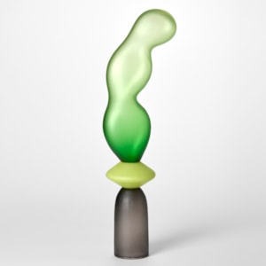 tall opaque sculpture consisting of three stacked forms a grey cup a lime yellow disc and an undulating bulbous balloon in green hand made from blown glass with a textured surface