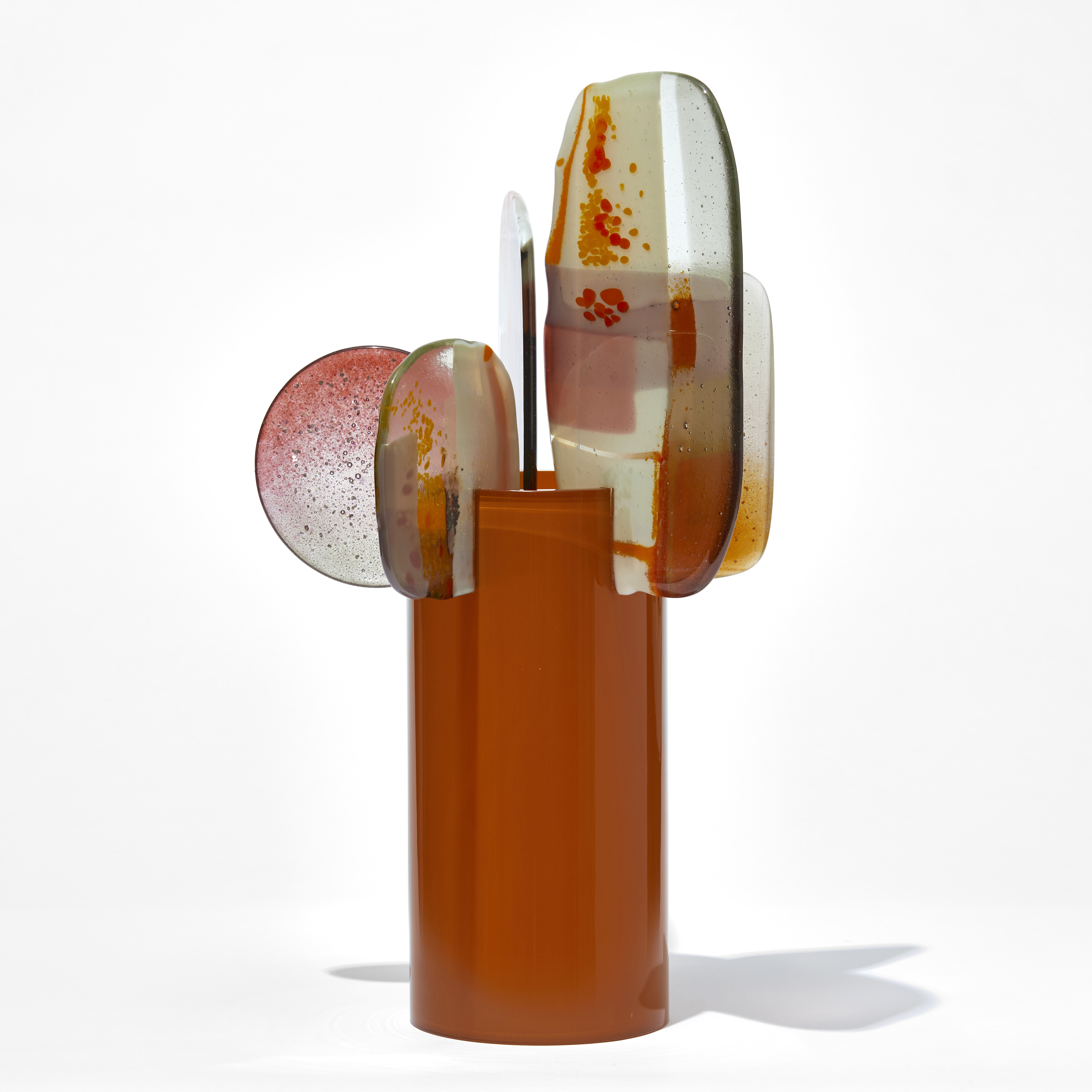 glossy burnt orange cylinder with five rounded finials attached to the top edge with pink clear yellow red and orange abstract patterns hand made from blown and fused glass