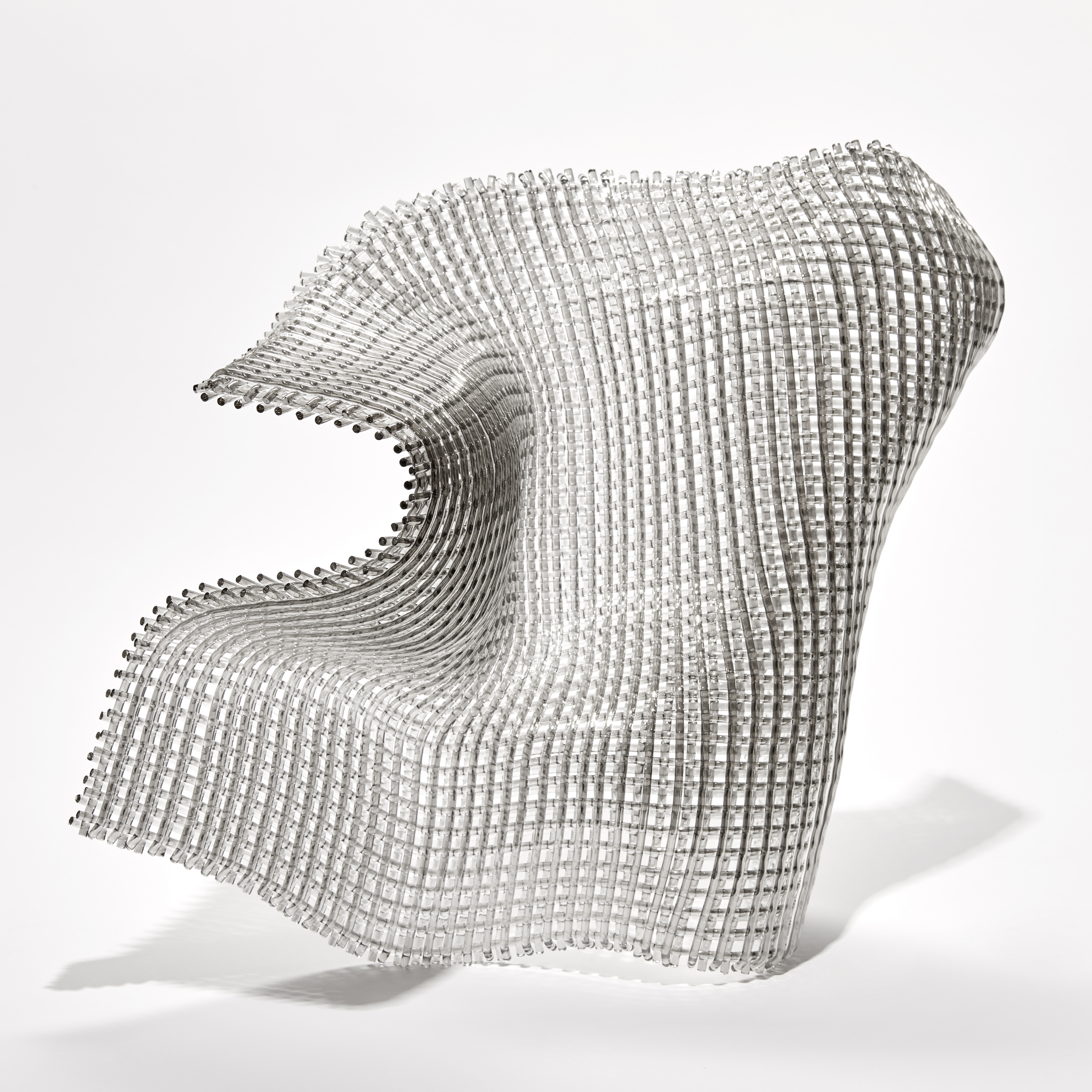 standing woven layered sheet formed from clear threads with an undulating form mimicking a fluttering piece of fabric in mid air hand made from glass with a fine silver coating on one side