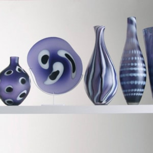 five purple hand blown glass vases in different shapes and patterns