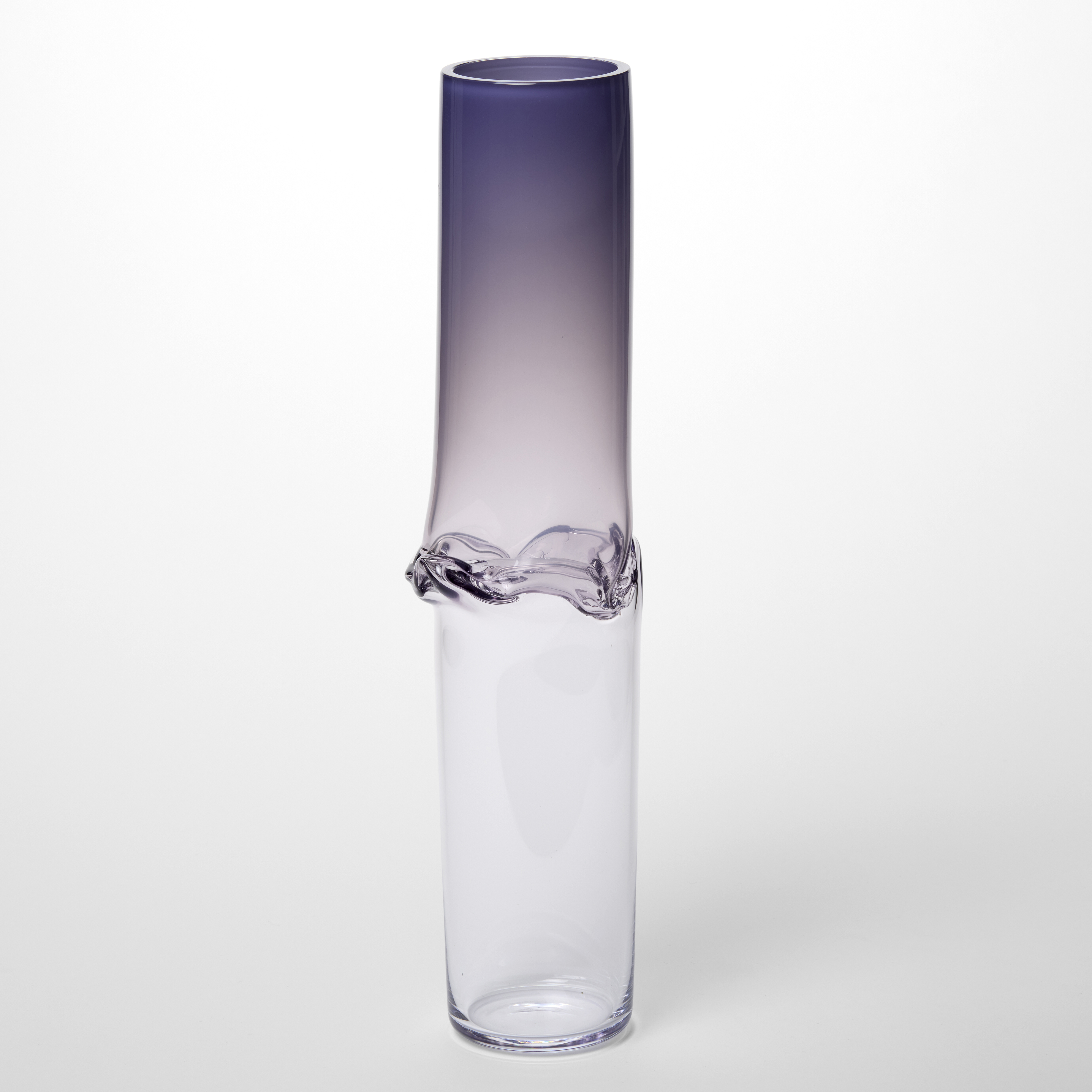 tall cylindrical vase form with the first half in fading transparent purple fading to a creased waist and clear below this point to the base hand made from blown glass