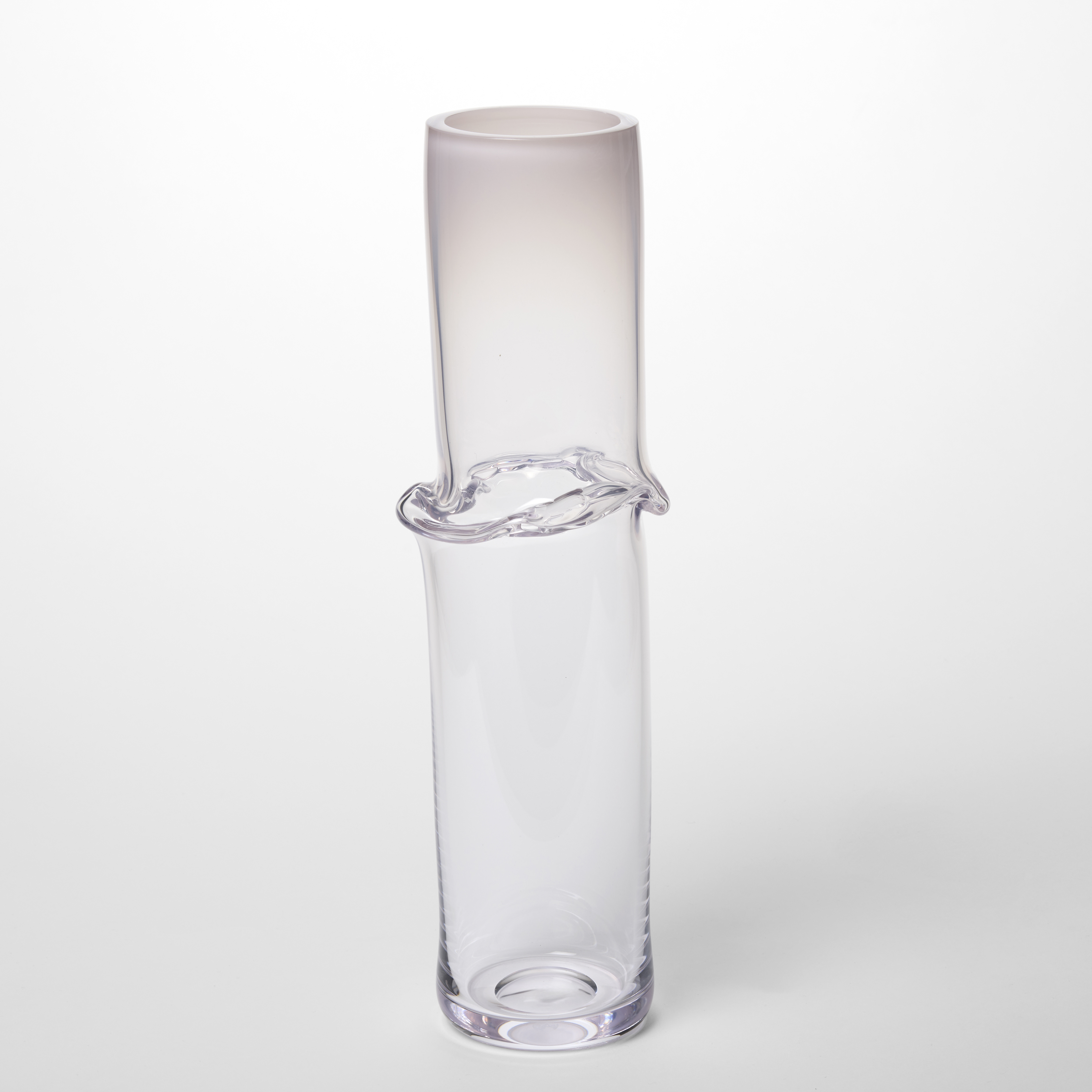 tall skinny transparent tubular vessel with an opaque pink top fading to clear at the base with an undulating creased band at the waist hand made from blown glass