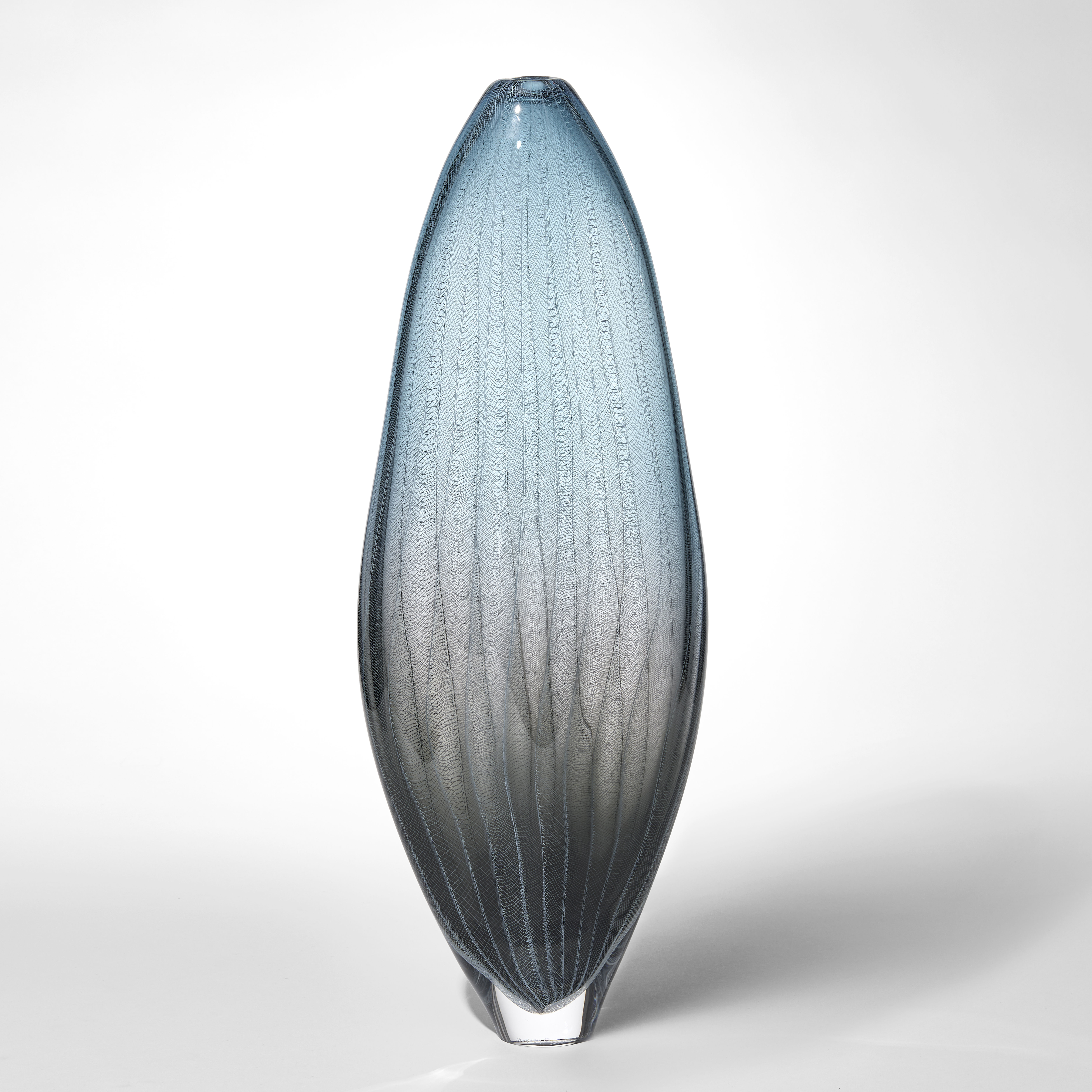 tall elegant slightly widening soft amorphous shaped transparent vase with grey at the base fading to soft steel blue at the top with a very fine lattice pattern covering the surface hand made from blown glass