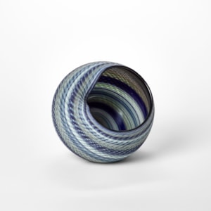 woven textured round basket with large side opening created from interwoven canes in indigo blue soft grey jade and celadon hand made from blown glass
