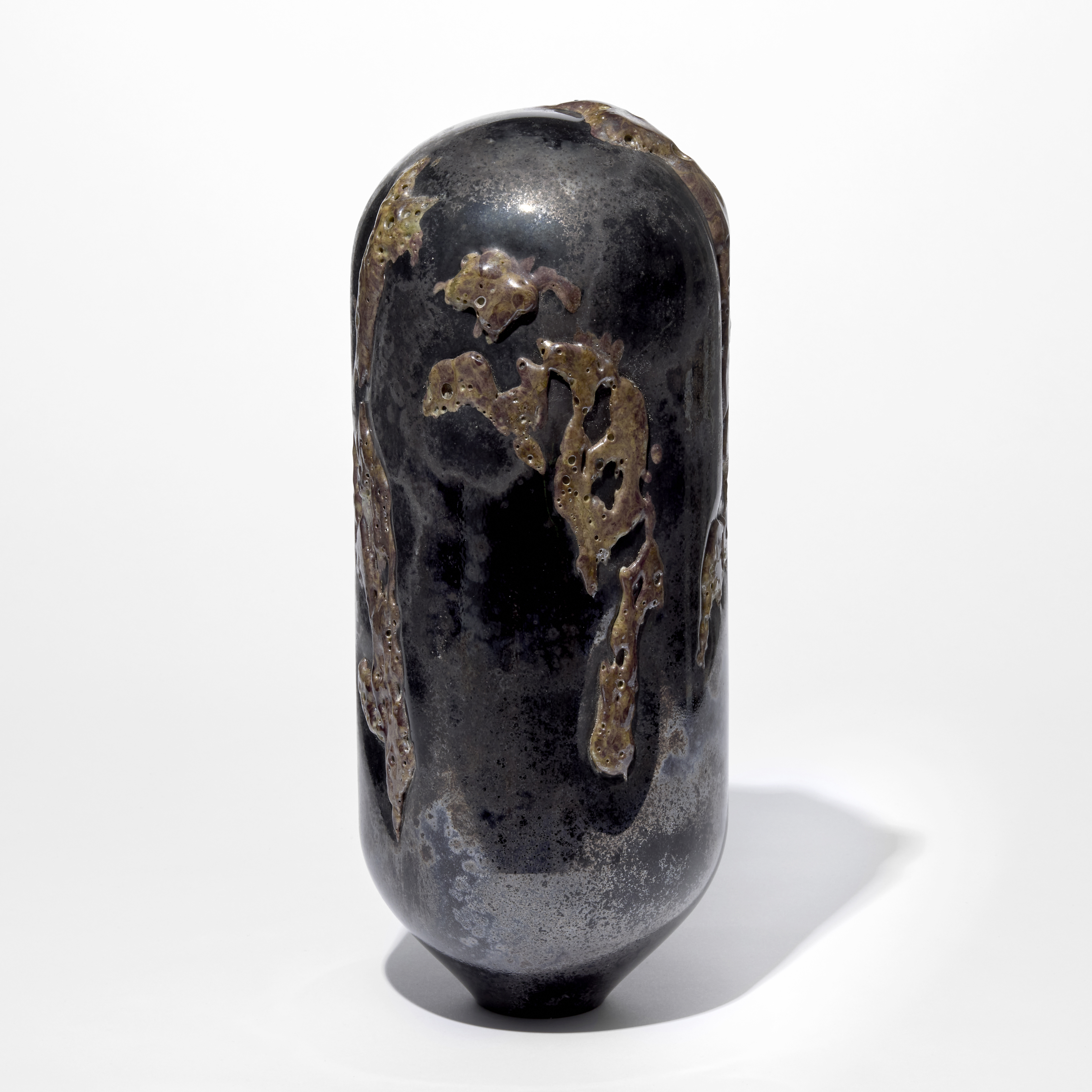 tall standing black and rust coloured sculpture with rounded top and tapered base covered in an organic sprawling surface texture hand made from glass
