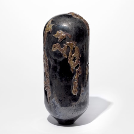 tall standing black and rust coloured sculpture with rounded top and tapered base covered in an organic sprawling surface texture hand made from glass