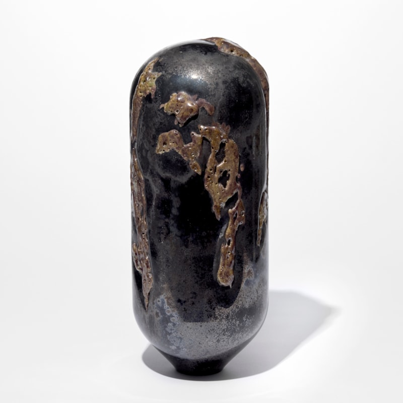 tall standing black and rust coloured sculpture with rounded top and tapered base covered in an organic sprawling surface texture hand made from glass