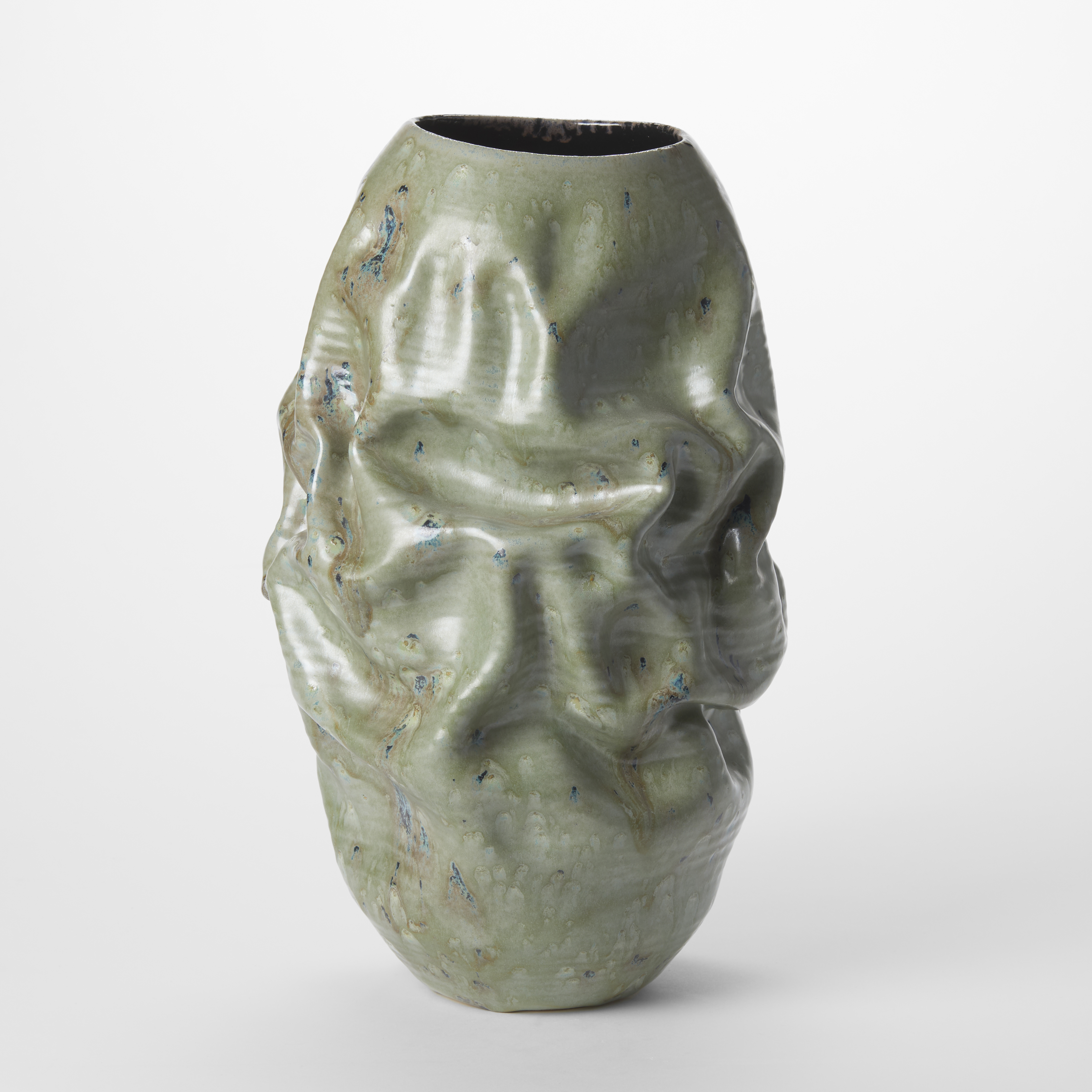 softly creased standing ovoid vessel with dark interior and oval opening with a jade green satin outer colour with dark blue specks hand made and thrown from clay