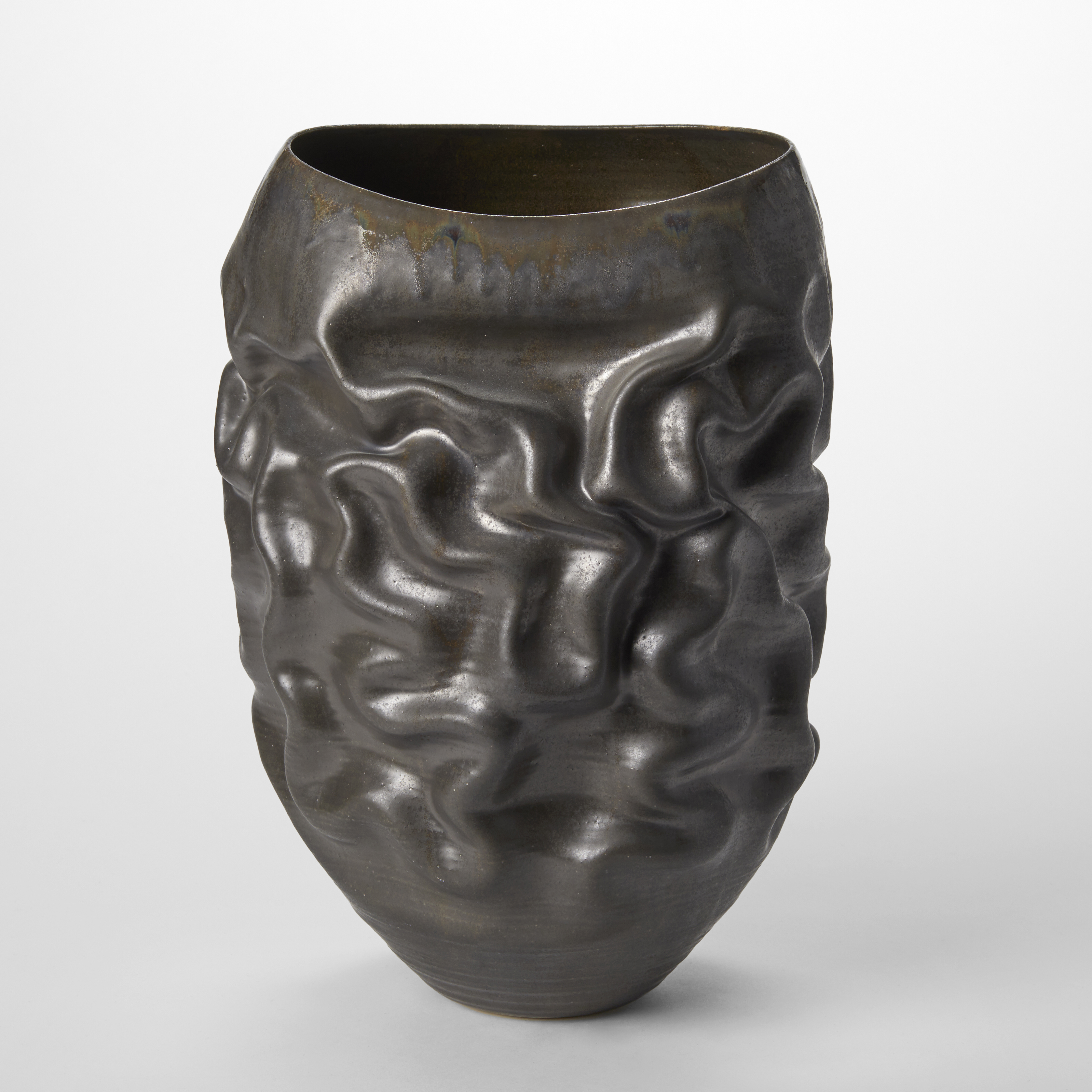 blunt ovoid black dark bronze sculptural vessel with the soft undulating creases all over the surface and wide dipping oval opening at the top hand made from thrown clay