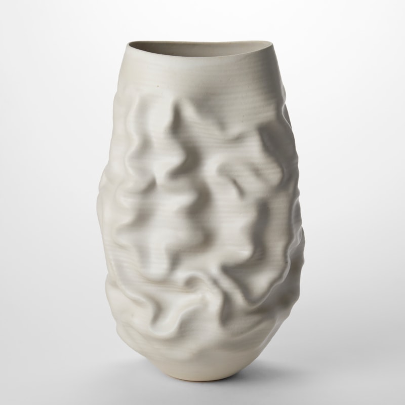 tall white ovoid sculptural vessel with the top cut off to a sweeping wide oval opening with soft undulations and creases across the surface hand made from thrown clay
