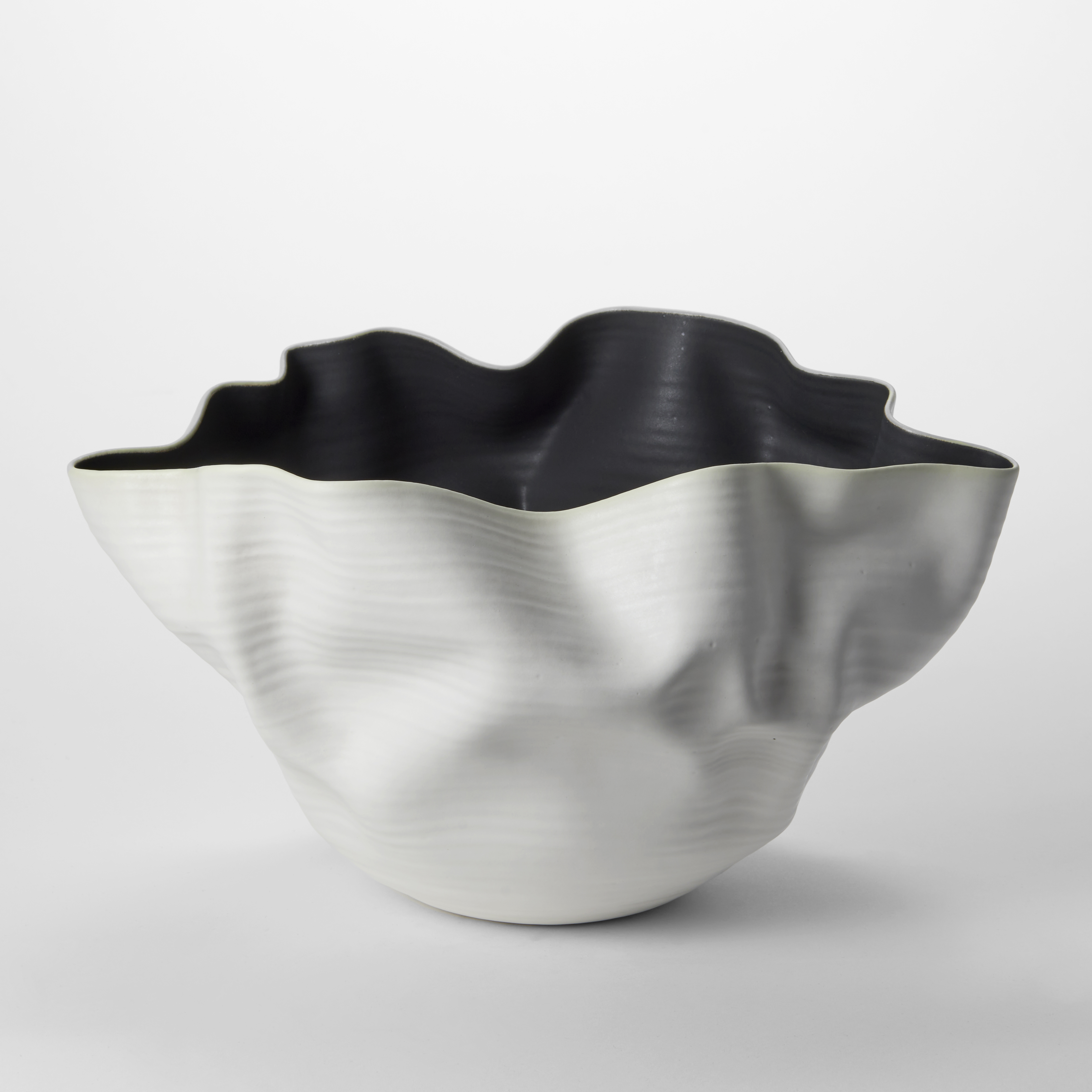 softly creased widening and flaring centrepiece with a matt white exterior and black interior hand thrown from white saint thomas clay