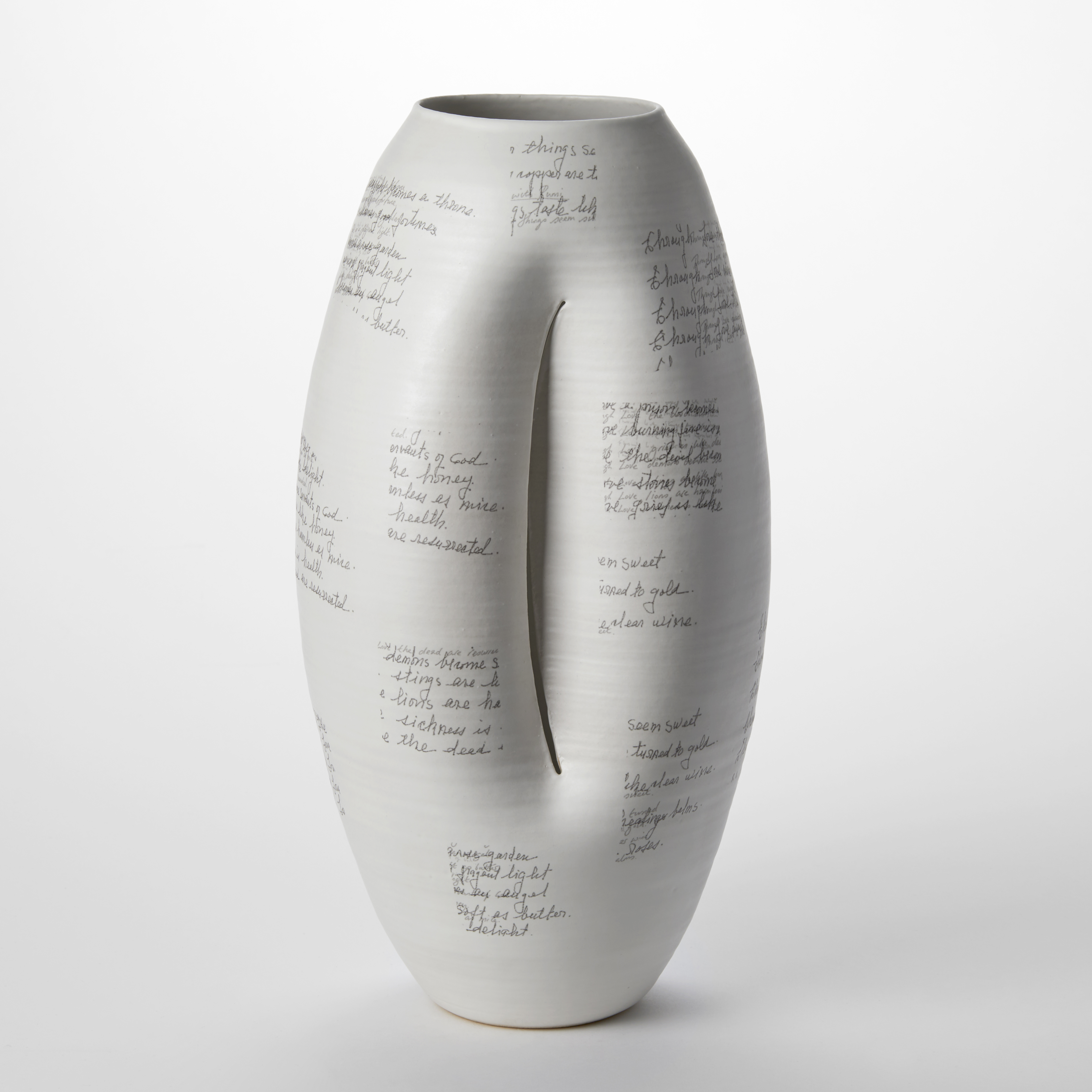 tall white oval vessel with crescent moon slit at the front and with square patches of black handwriting on the surface hand made from clay