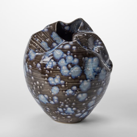 black small round sculptural vessel with creased and gathered top opening with blue exploding splodges all over the surface hand thrown from clay