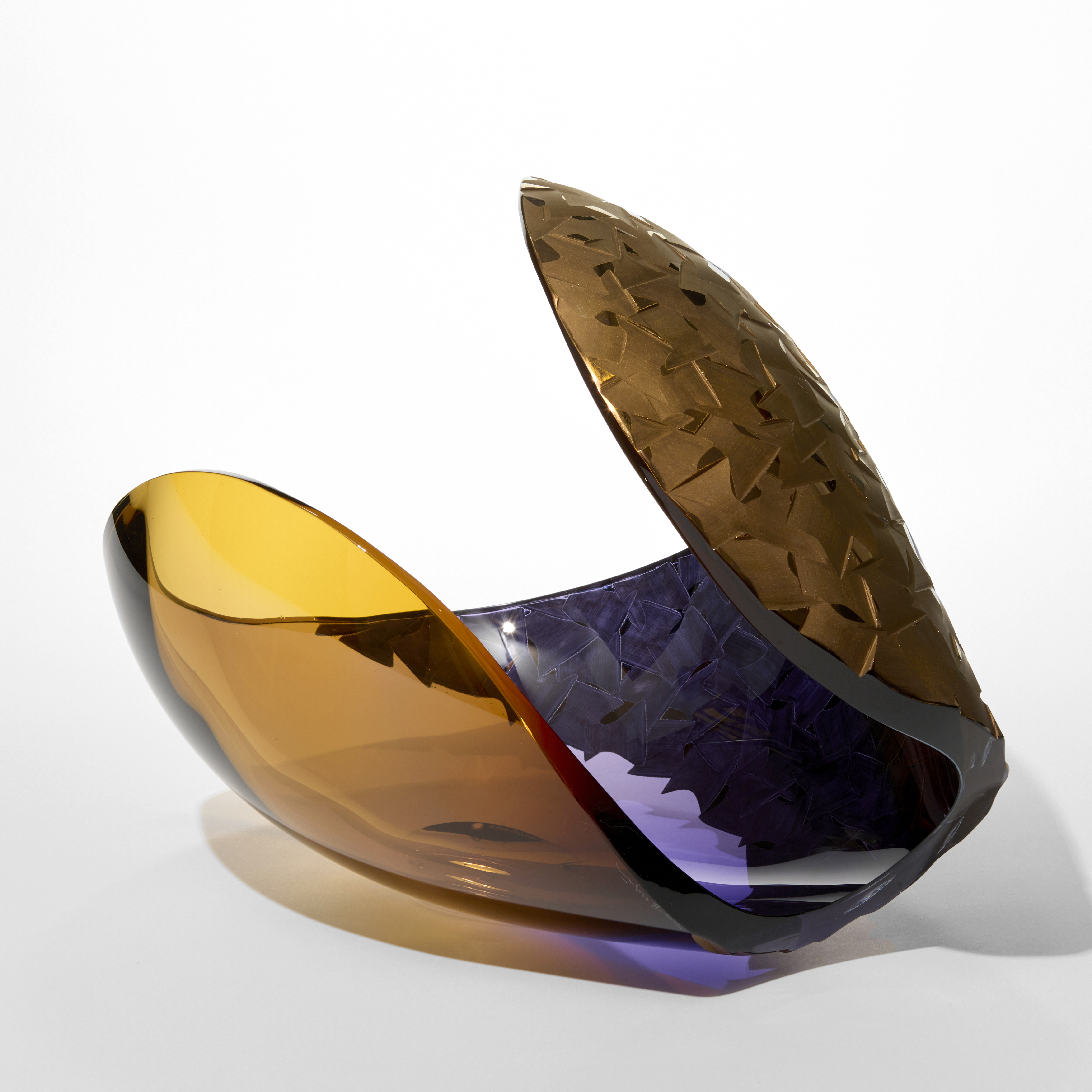 curled rounded form like a simplified shell in transparent amber fading to purple with one side covered in a repeat incised graphic pattern hand blown from glass with matt twenty three carat gold