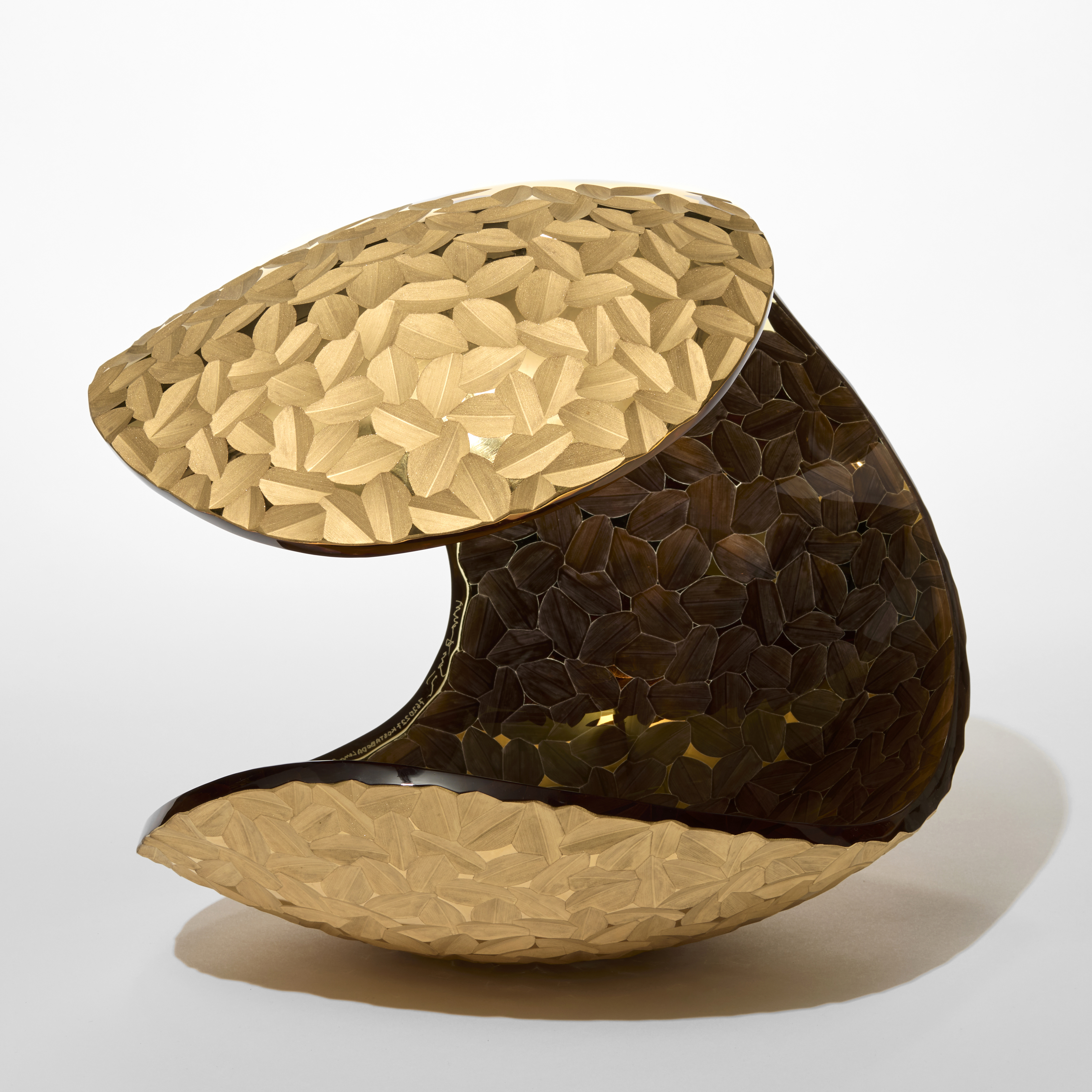 curled over perched rounded form with the entire outer surface covered in a repeat cut tessellated pattern encased in matt gold hand blown from glass with a matt twenty three carat gold coating