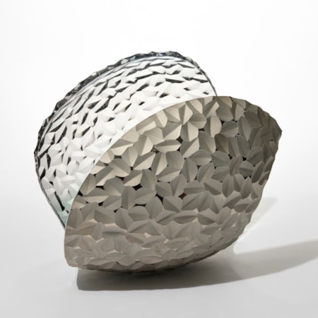 curled simplified shell like shape with the surface covered in repeat incised tessellated pattern handblown from light grey glass with a one side covered in matt silver lustre