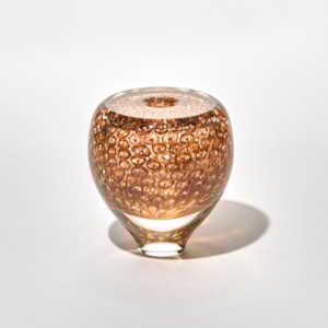 round glossy vase with a flat top surface and small middle opening with a surface pattern of repeat circular small motifs with central dots in brown and dark red with a tapering transparent foot hand made from blown glass