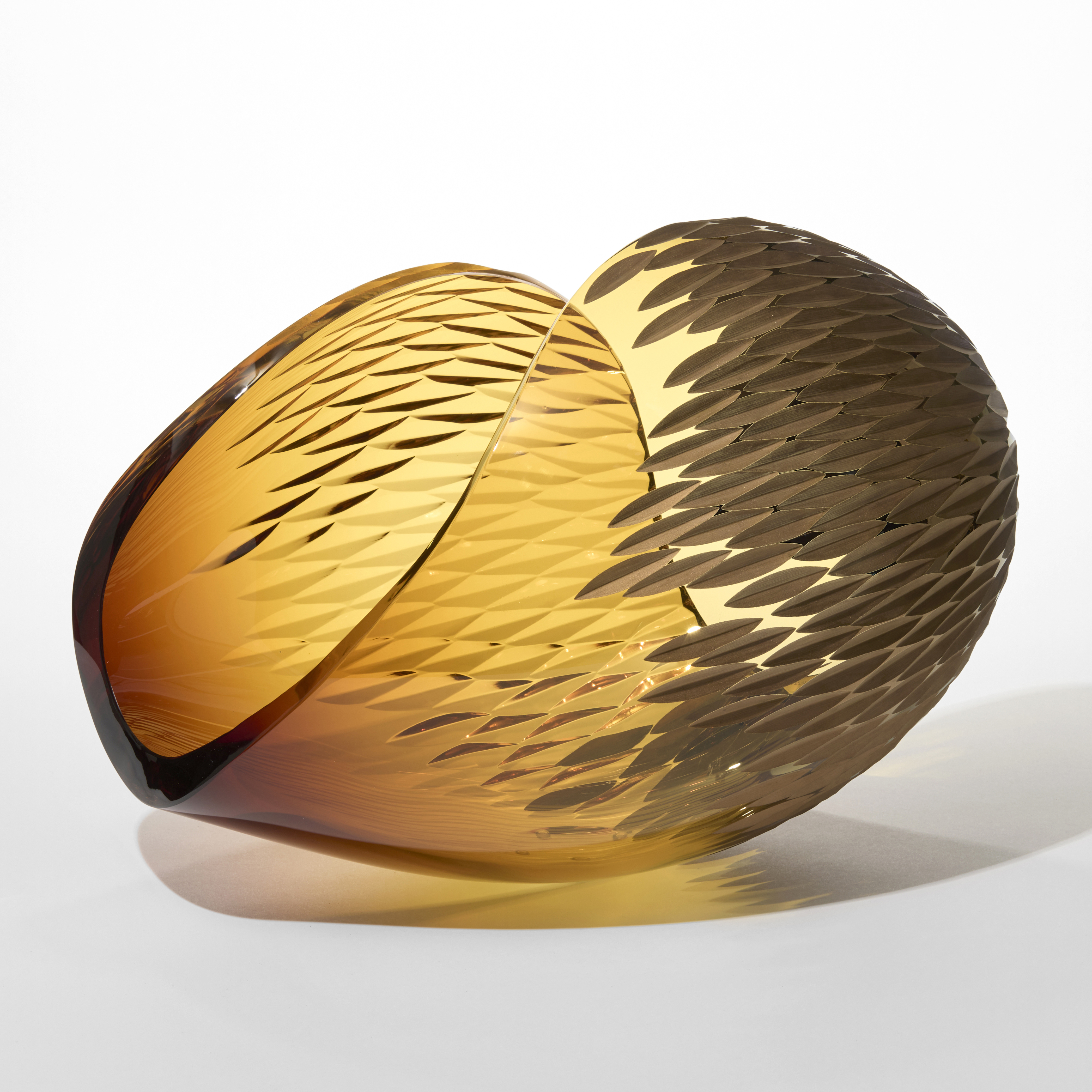 curled ovoid form in transparent amber with both sides partially covered in tessellated incised rounded diamond shapes which are matt gold on one side hand blown from glass and twenty three carat gold