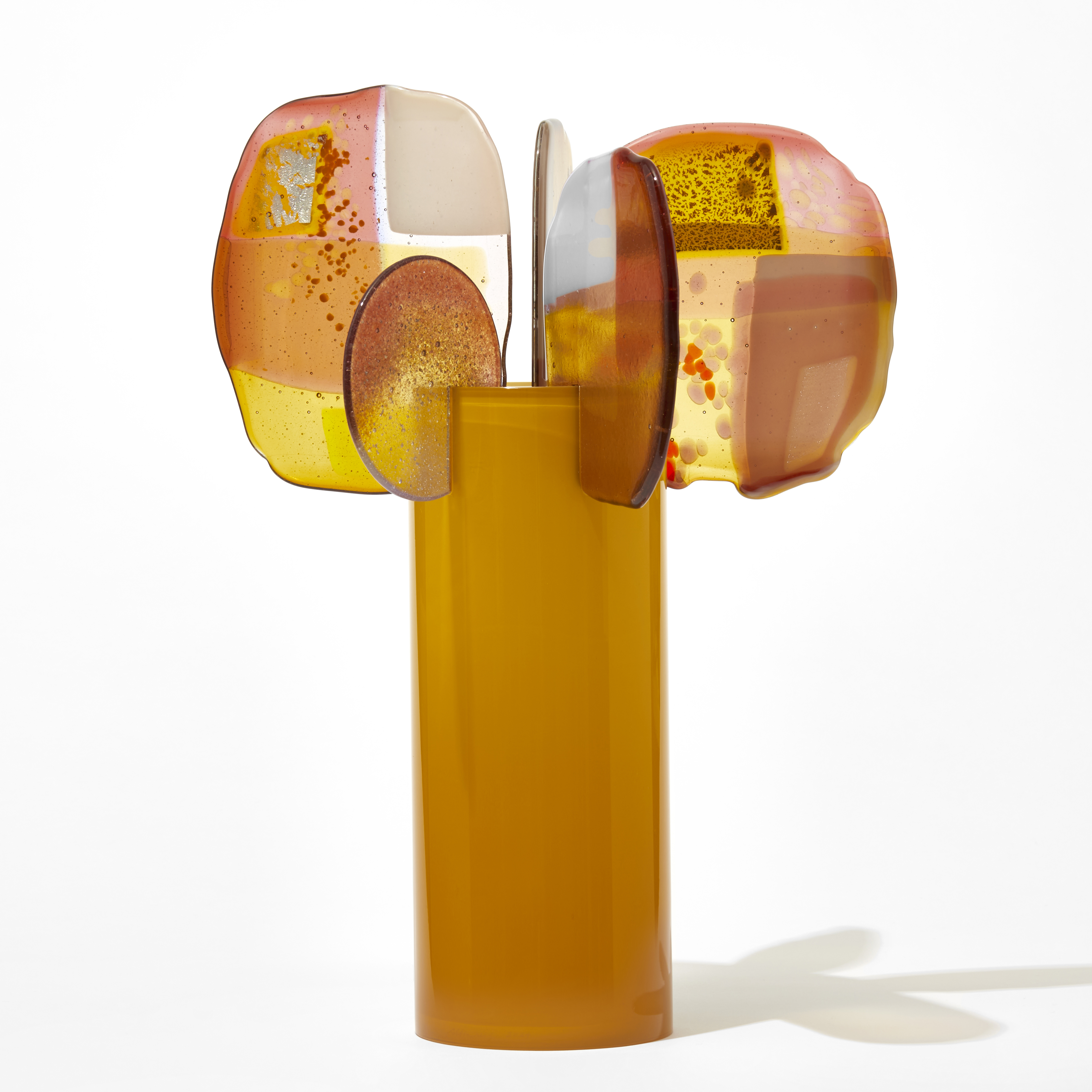 glossy opaque egg yellow cylinder with five rounded fins attached to the top rim with abstract patterns on each in pink white gold orange and red hand made from blown and fused glass