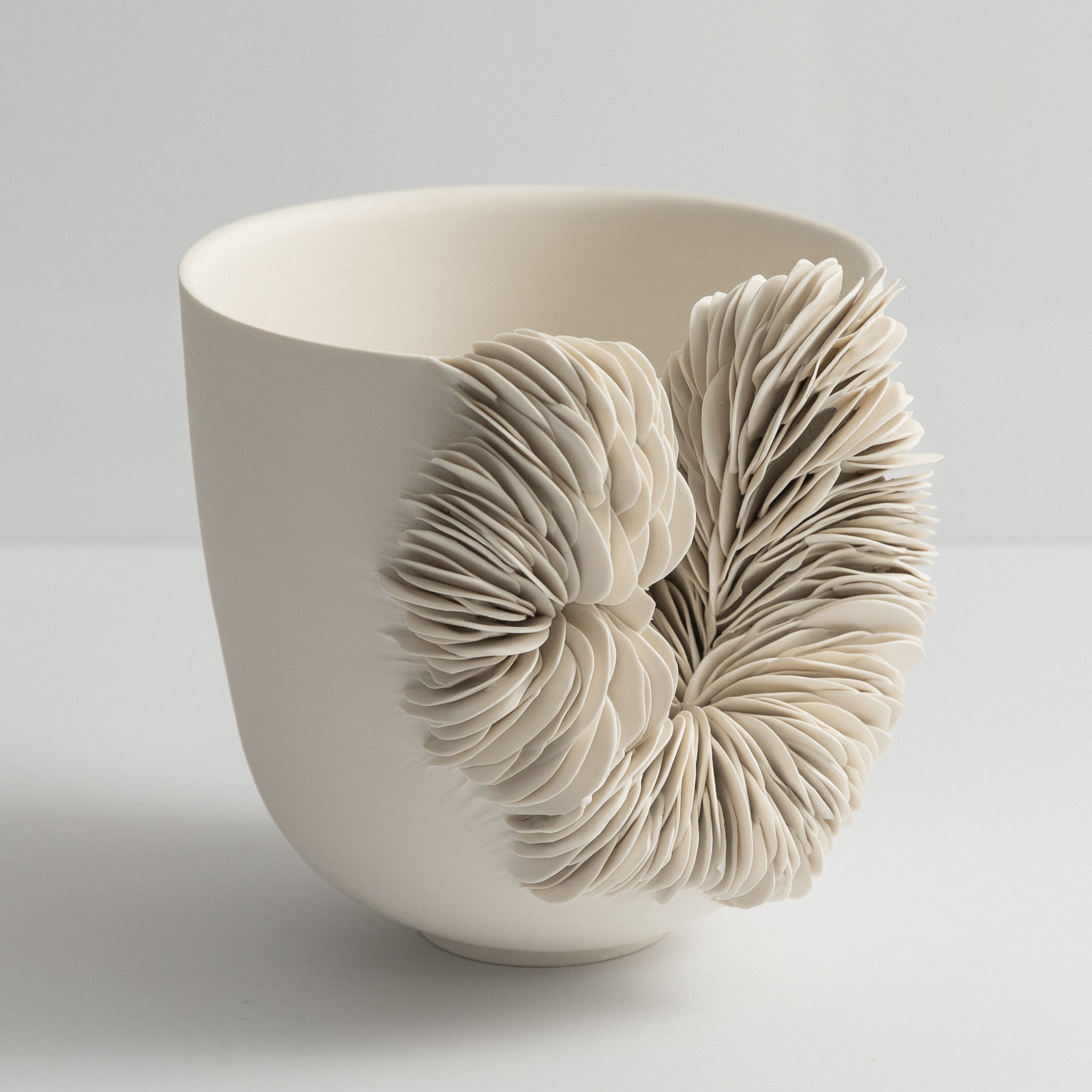 off white round flaring bowl with tapering base and the front section cut away and the gap filled with stacked shard hand made from porcelain