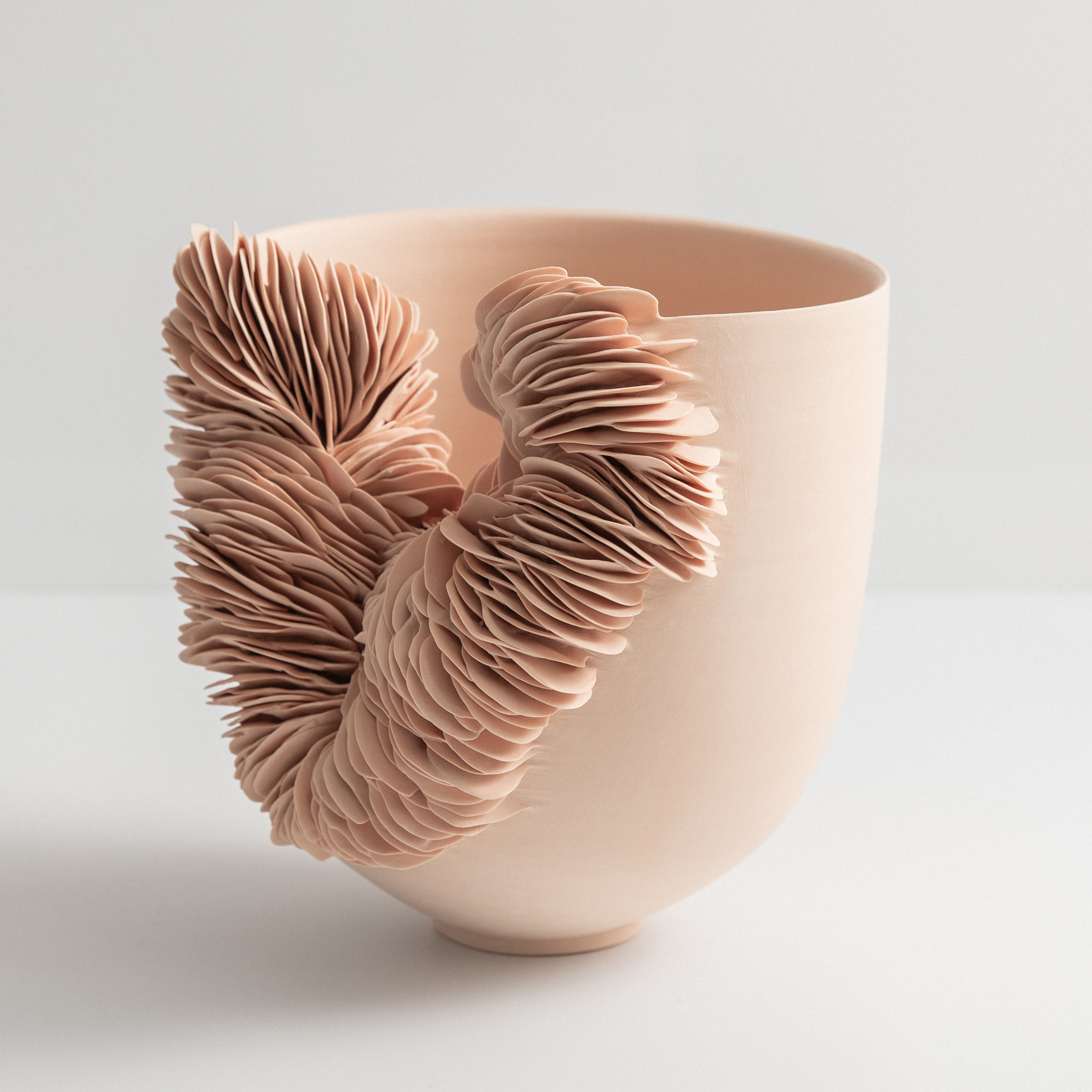 soft rose pink thrown bowl with one side cut away and filled with stacked ceramic shards in the same colour hand made from porcelain
