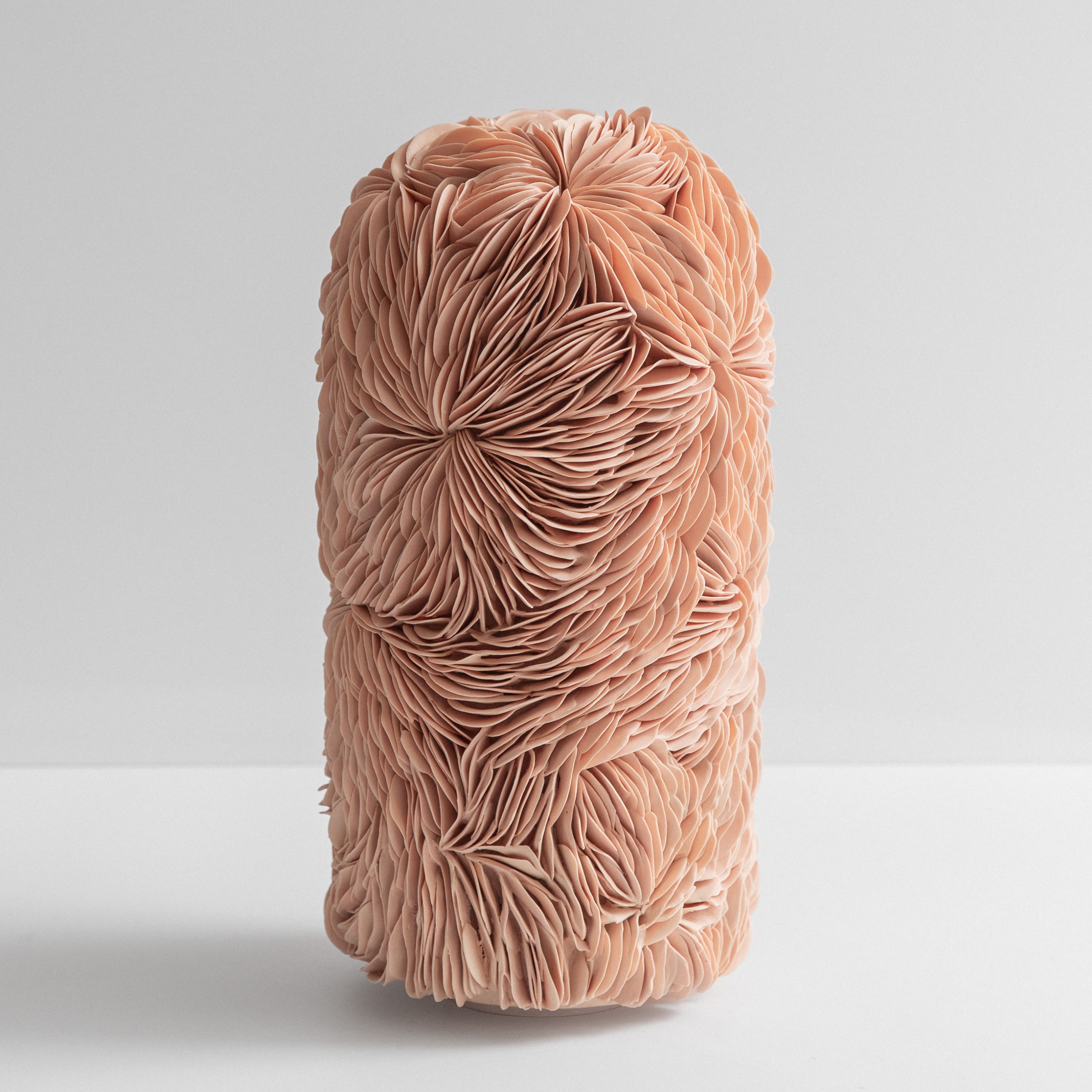 tall column shaped form with a domed rounded top and small opening covered in interlocking curved soft rose salmon coloured ceramic shards hand made from porcelain