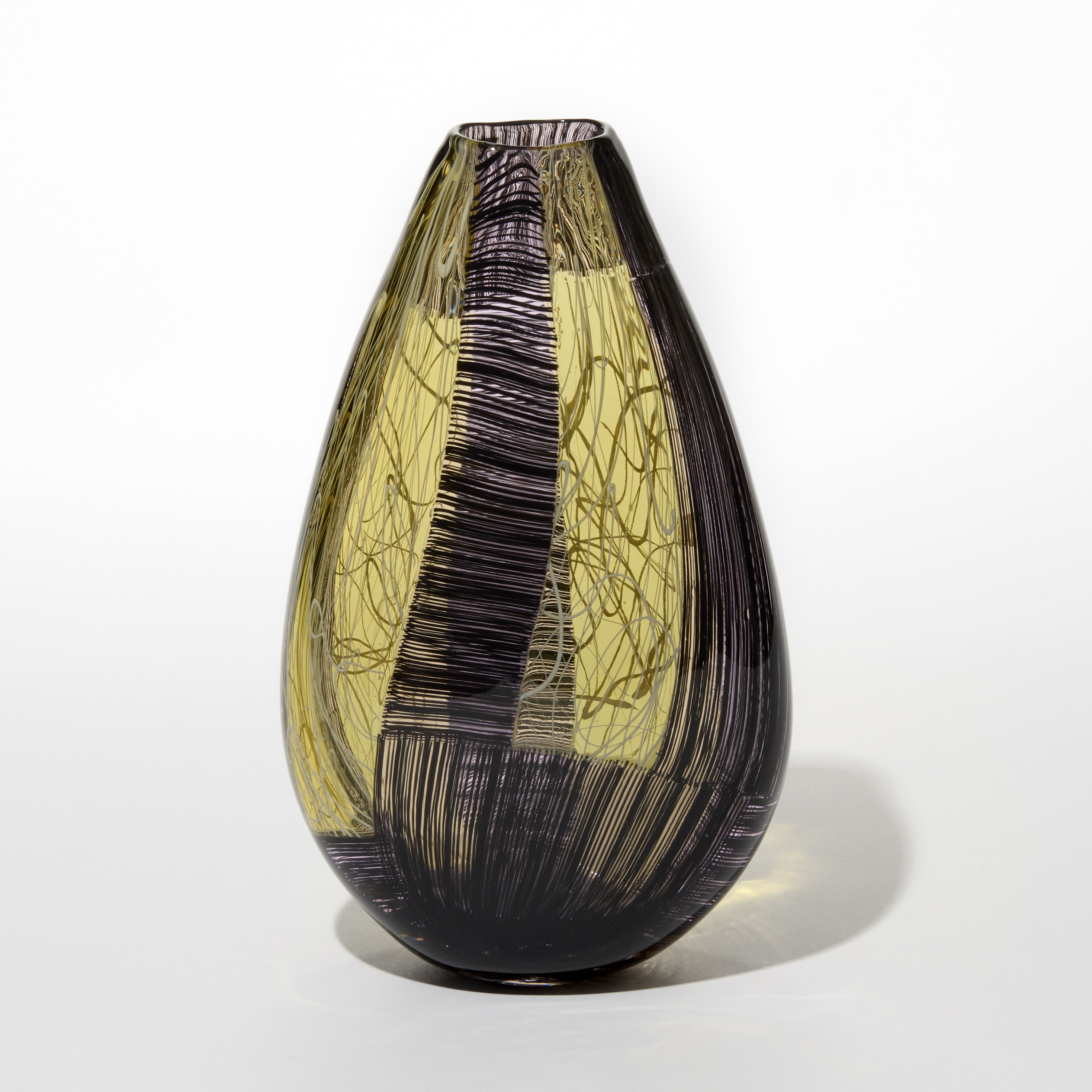 teardrop shaped transparent vase with a narrow opening at the top with a translucent yellow base overlaid with bold vertical black stripes and fine linear detailing and delicate swirling patterns with fine scribble like lines within the yellow banded areas hand blown from glass