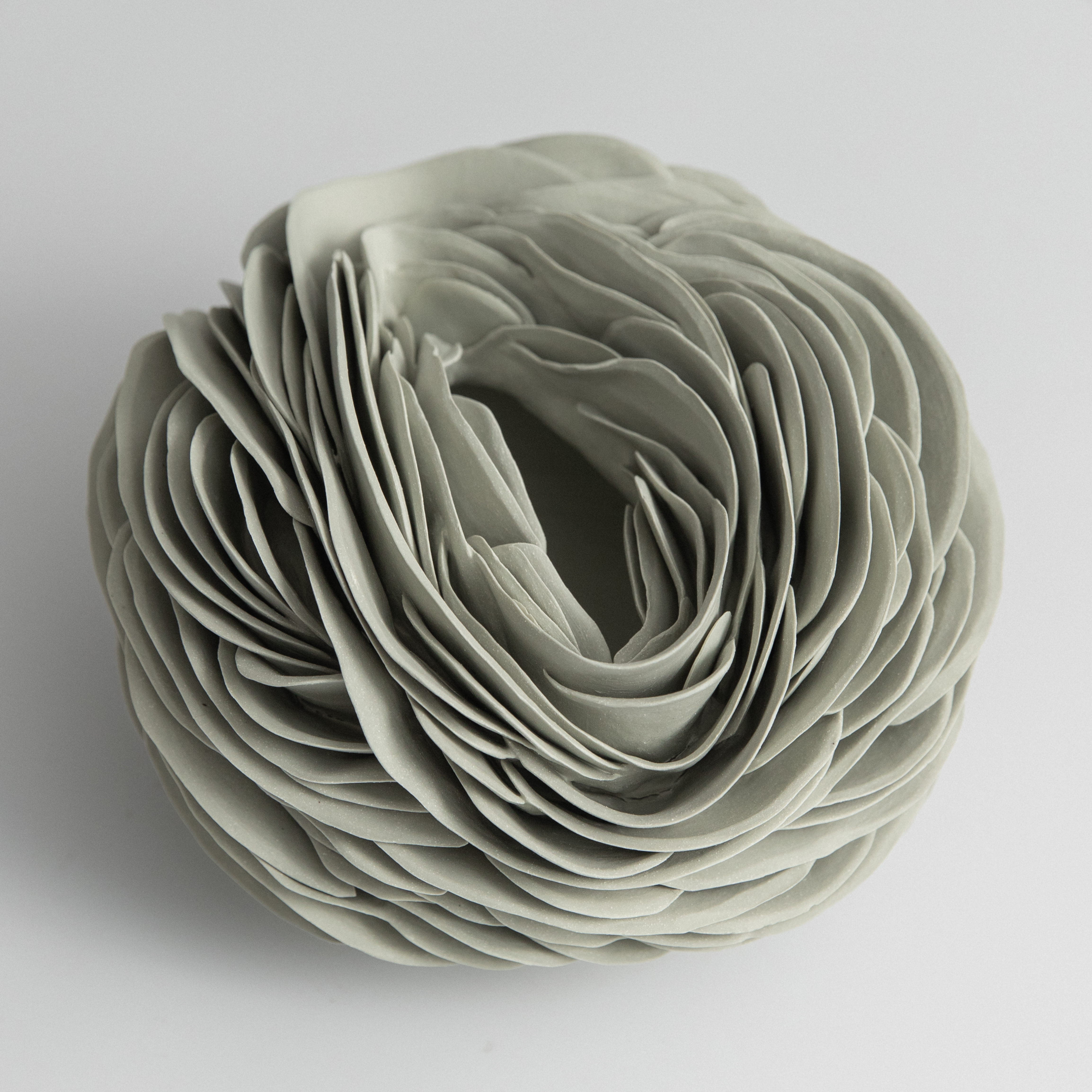 round soft green nest like vessel with the thin long top opening and the entire surface covered in curved interwoven shards hand made from coloured porcelain