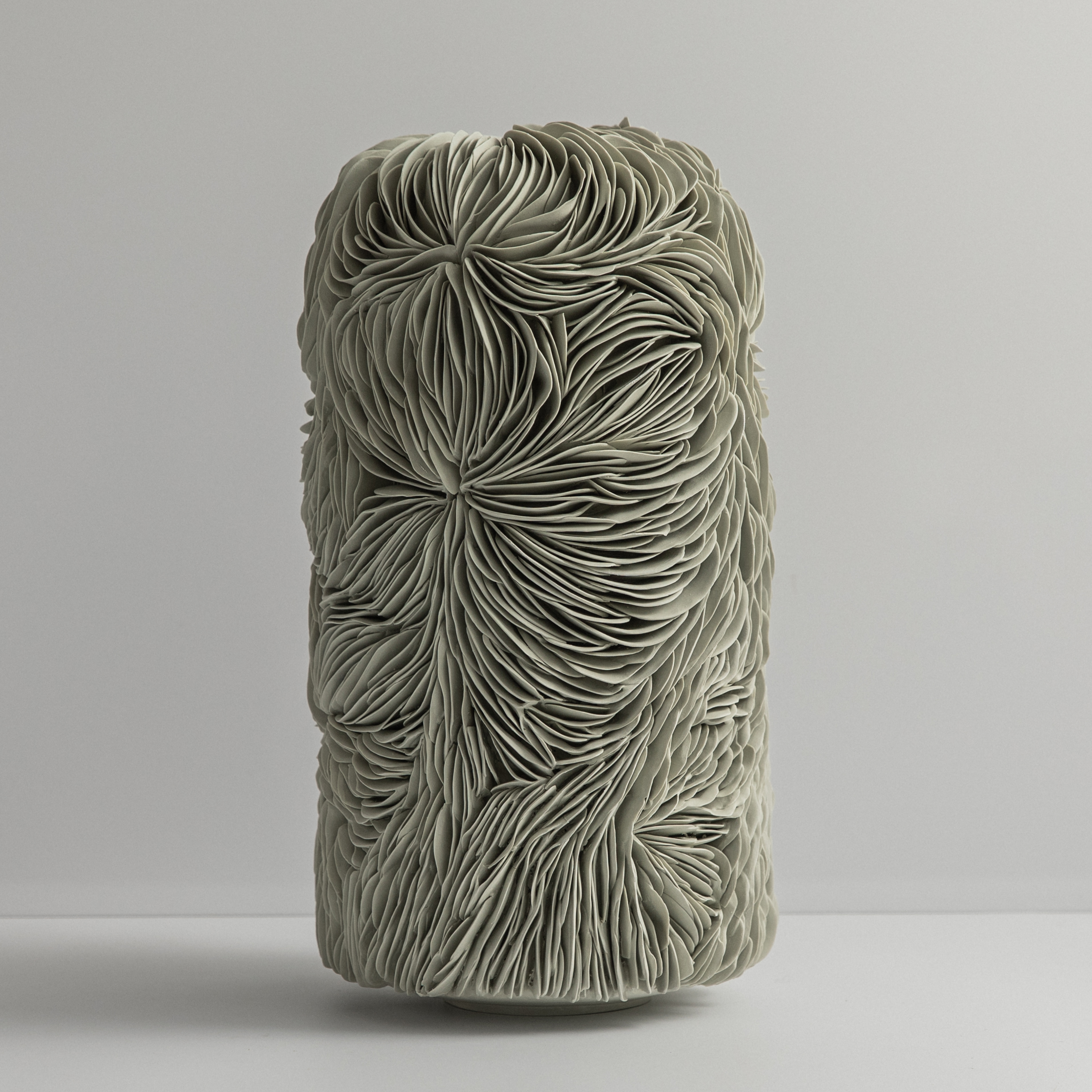 soft sage green standing column shaped form with domed top and small top opening covered in curved interlocking shards hand made from coloured porcelain