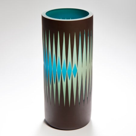tall cylindrical vase with a reverse diminishing geometric pattern of repeat stretched diamonds and pointed spikes in light jade green and turquoise with a black background handmade from glass