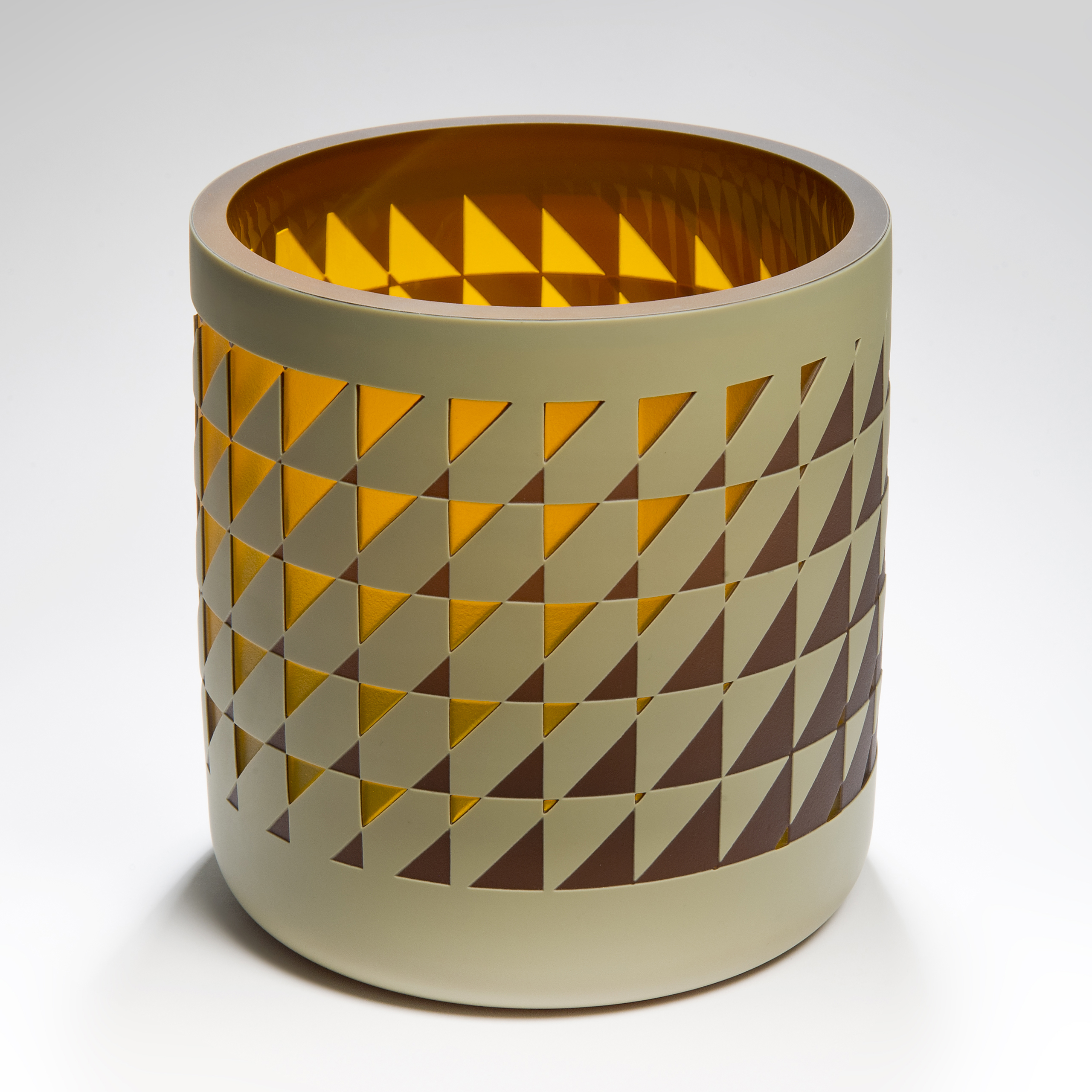 straight sided round tubular vase with an interwoven and reverse diminishing geometric pattern in brown amber and mustard with a glossy interior hand made from glass