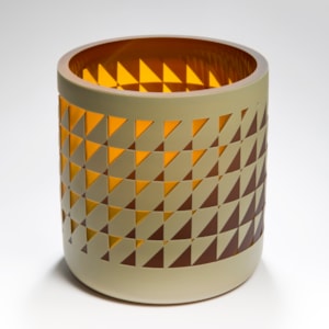 straight sided round tubular vase with an interwoven and reverse diminishing geometric pattern in brown amber and mustard with a glossy interior hand made from glass