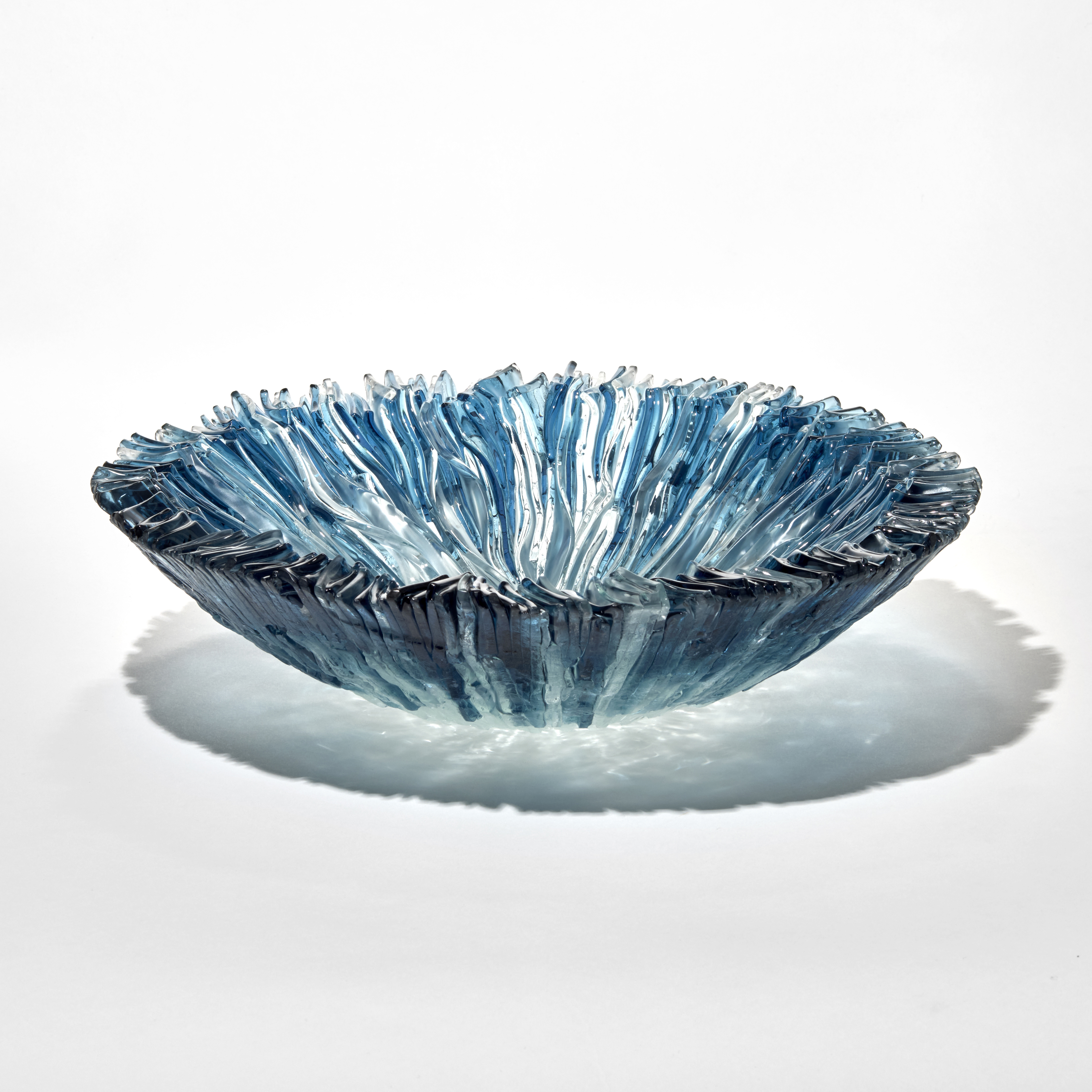round low semi transparent centrepiece with a feathered edge and soft ridges on the top surface in mingling aqua and light turquoise hand made from fused glass