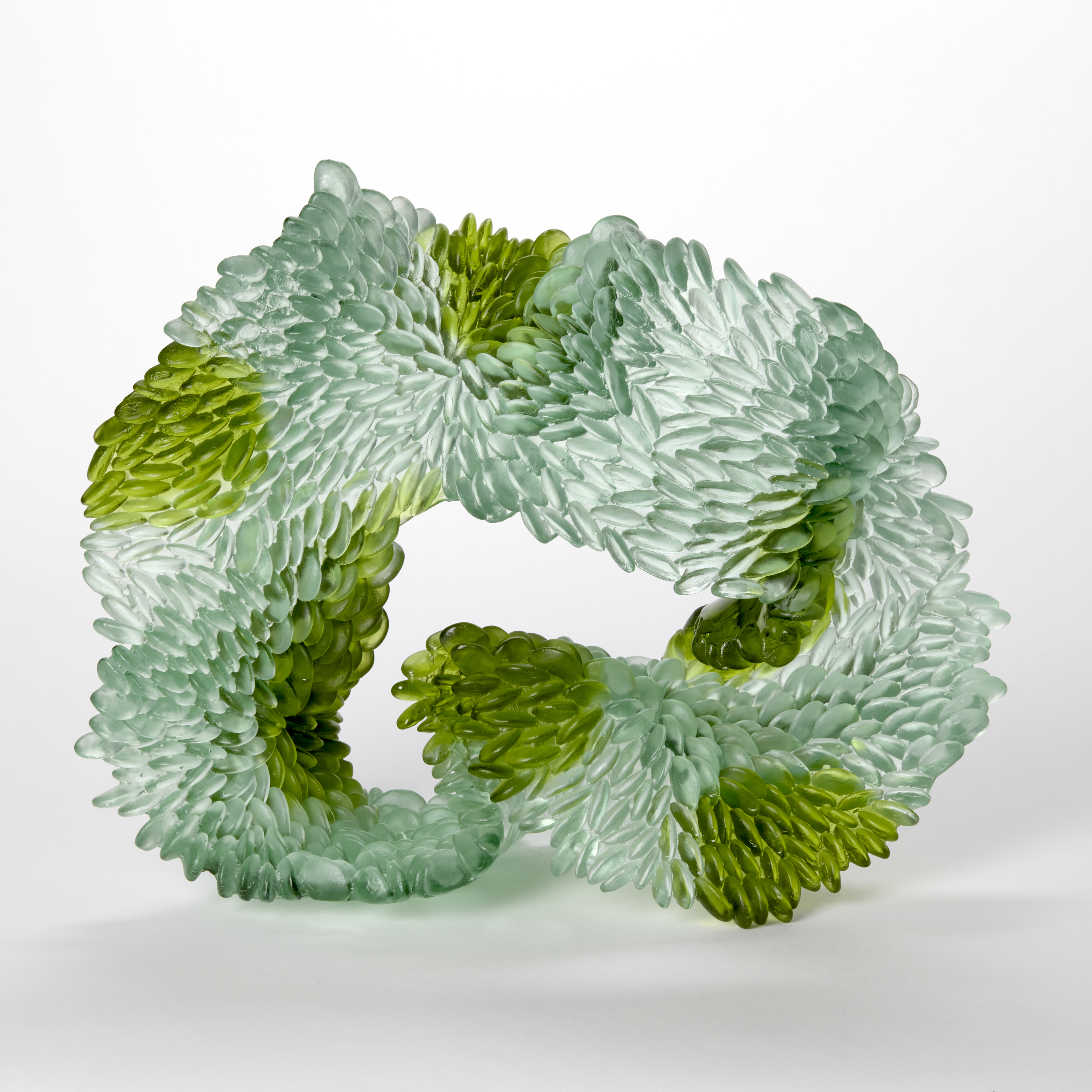 standing abstract looping and undulating sculpture in opaque jade and emerald green with the front surface covered in small raised scales hand made from cast glass
