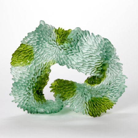 standing abstract looping and undulating sculpture in opaque jade and emerald green with the front surface covered in small raised scales hand made from cast glass
