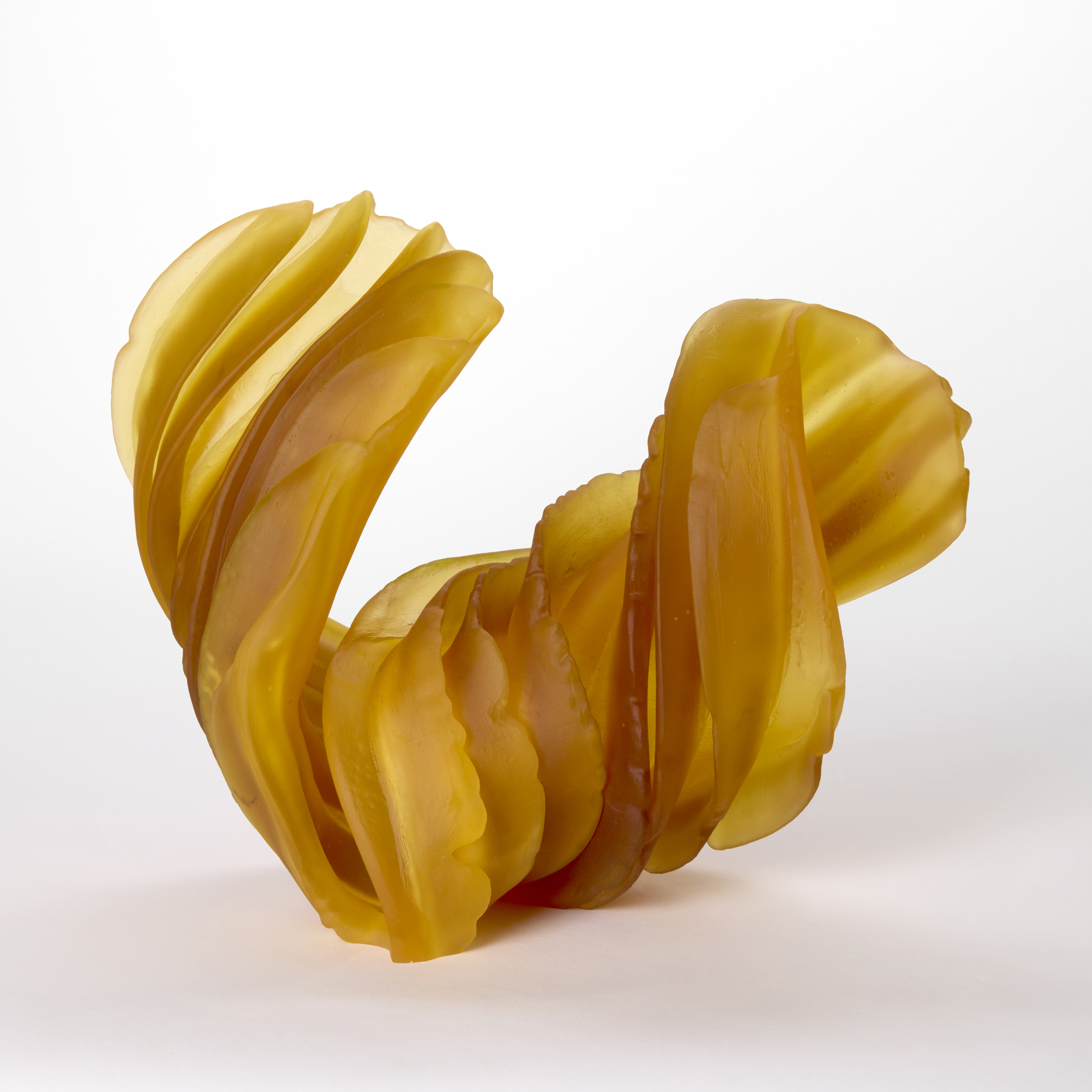 twisting and curling abstract form in opaque rich amber yellow with thick ridges each with organic frilly edges hand made from cast and sculpted glass 