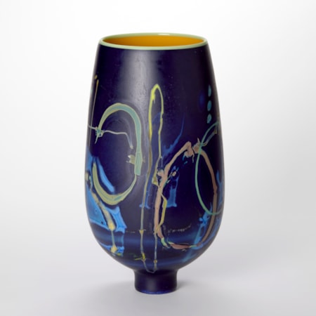 round bulbous vase tapering to a narrow foot in rich deep purple blue with surface meandering line abstract patterns in yellow mint blue and soft pink with a glossy interior in egg yolk yellow and a wide opening with a rim in citrus yellow hand made from blown glass