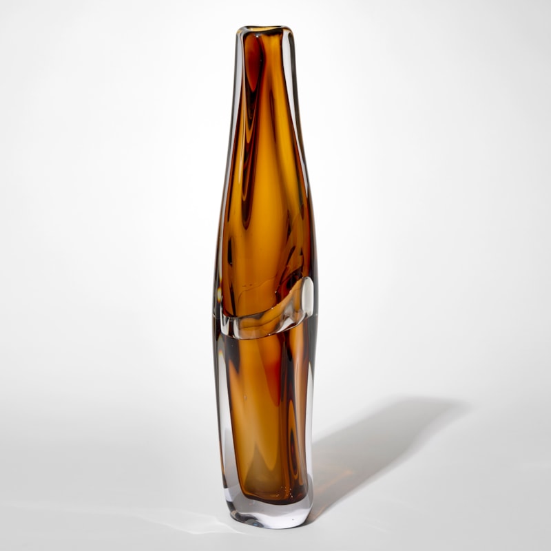 tall transparent slightly twisting vase with small top opening and layers in clear and amber brown with an undulating central belted section hand blown from glass