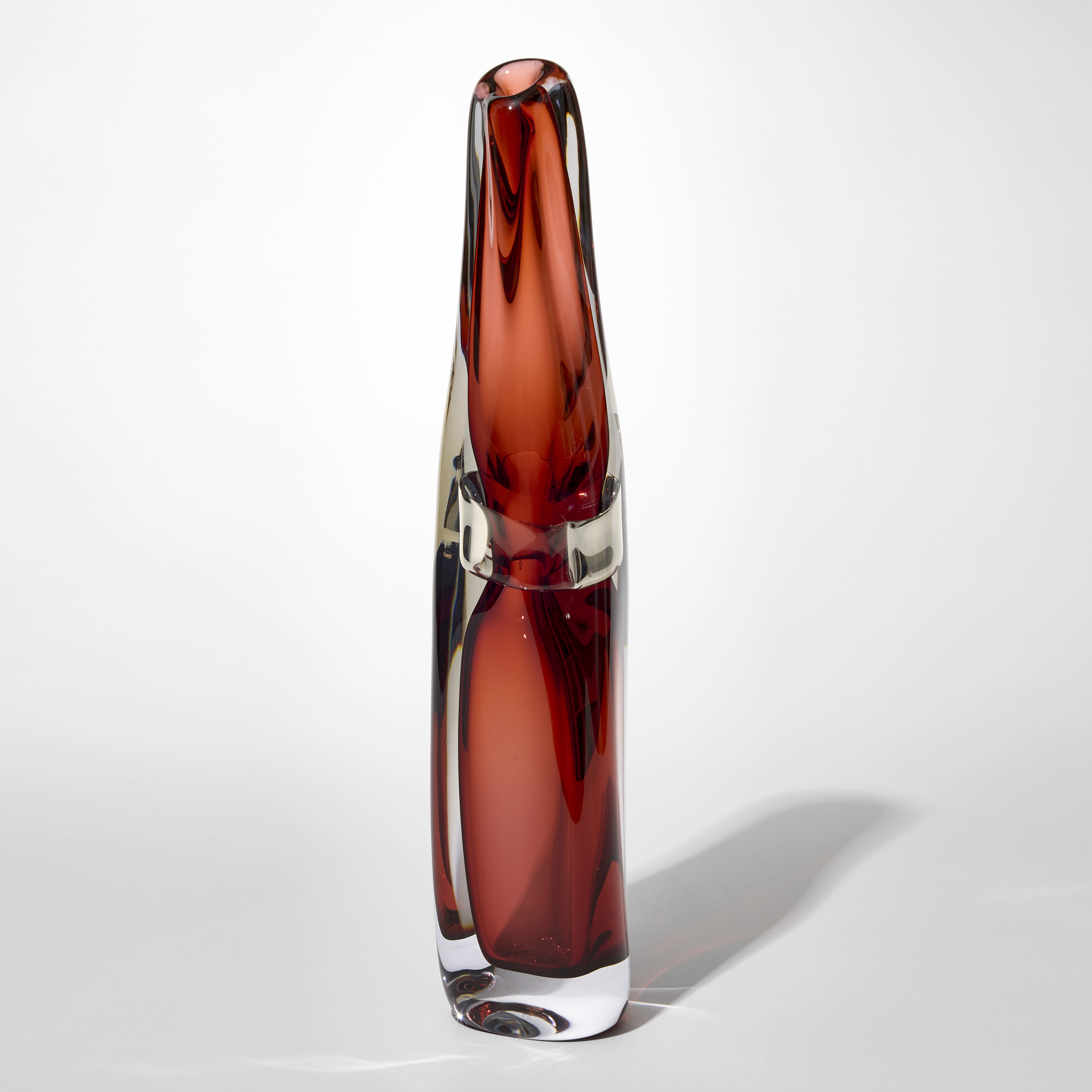 tall transparent sculptural vase with small top opening and layers in clear and sienna with a clear banded section trapped within at the waist of the piece hand blown from glass