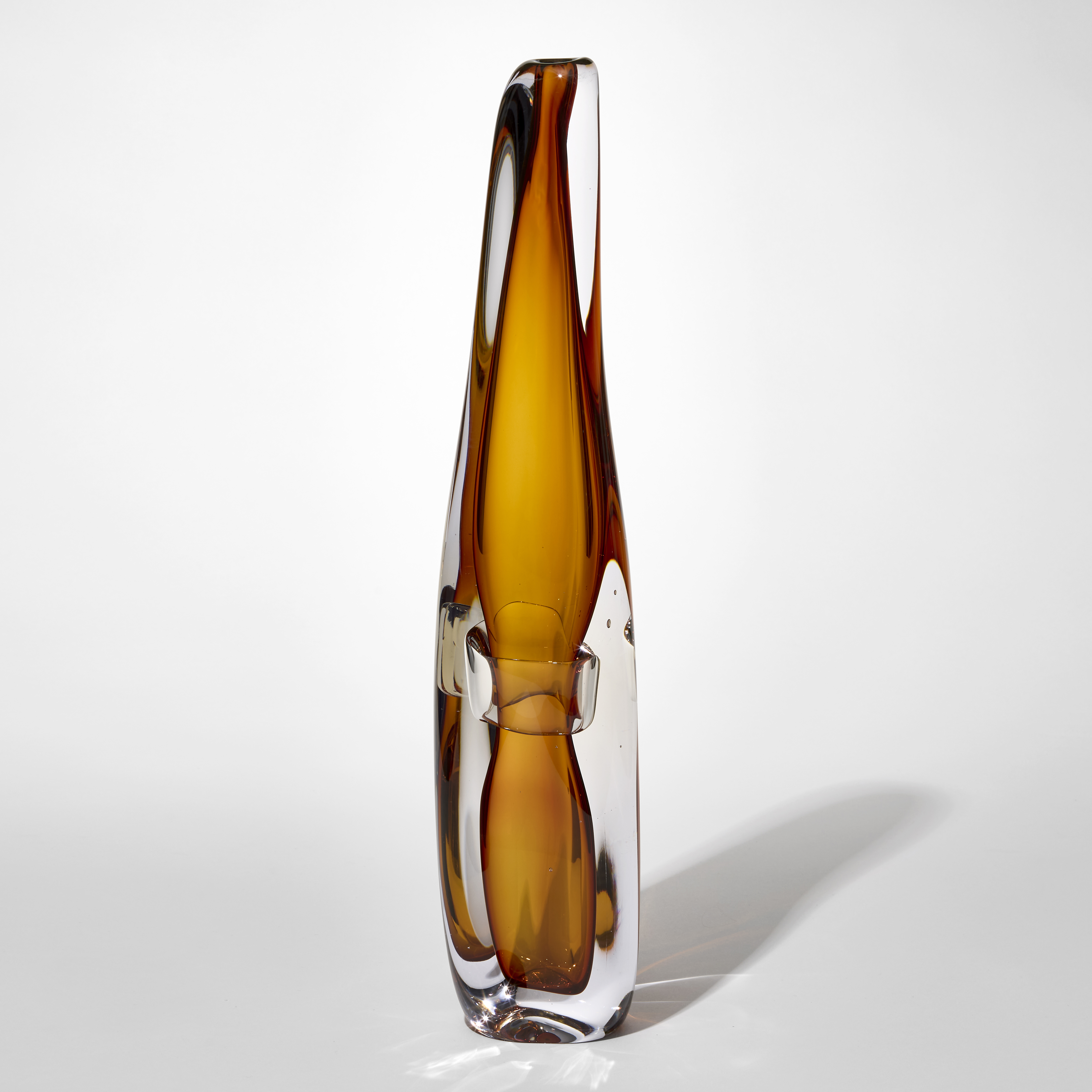tall tapering transparent vase with thick clear outer layer and inner undulating honey amber layer with pinched in section a third up from the bottom hand blown from glass