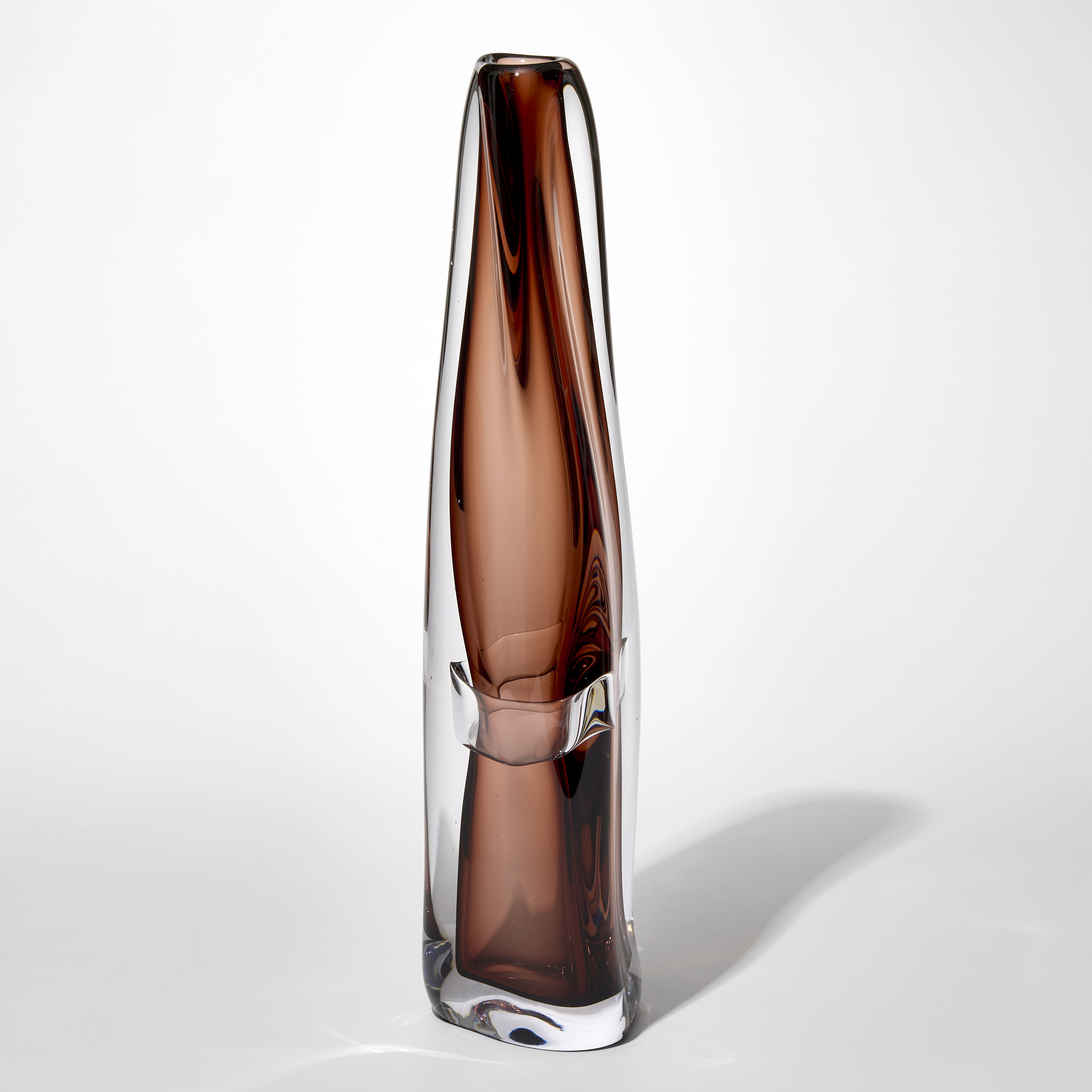 tall transparent vase with fluid lines and slighting tapering twisting shape with two layers one in clear then an inner in warm brown hand blown from glass