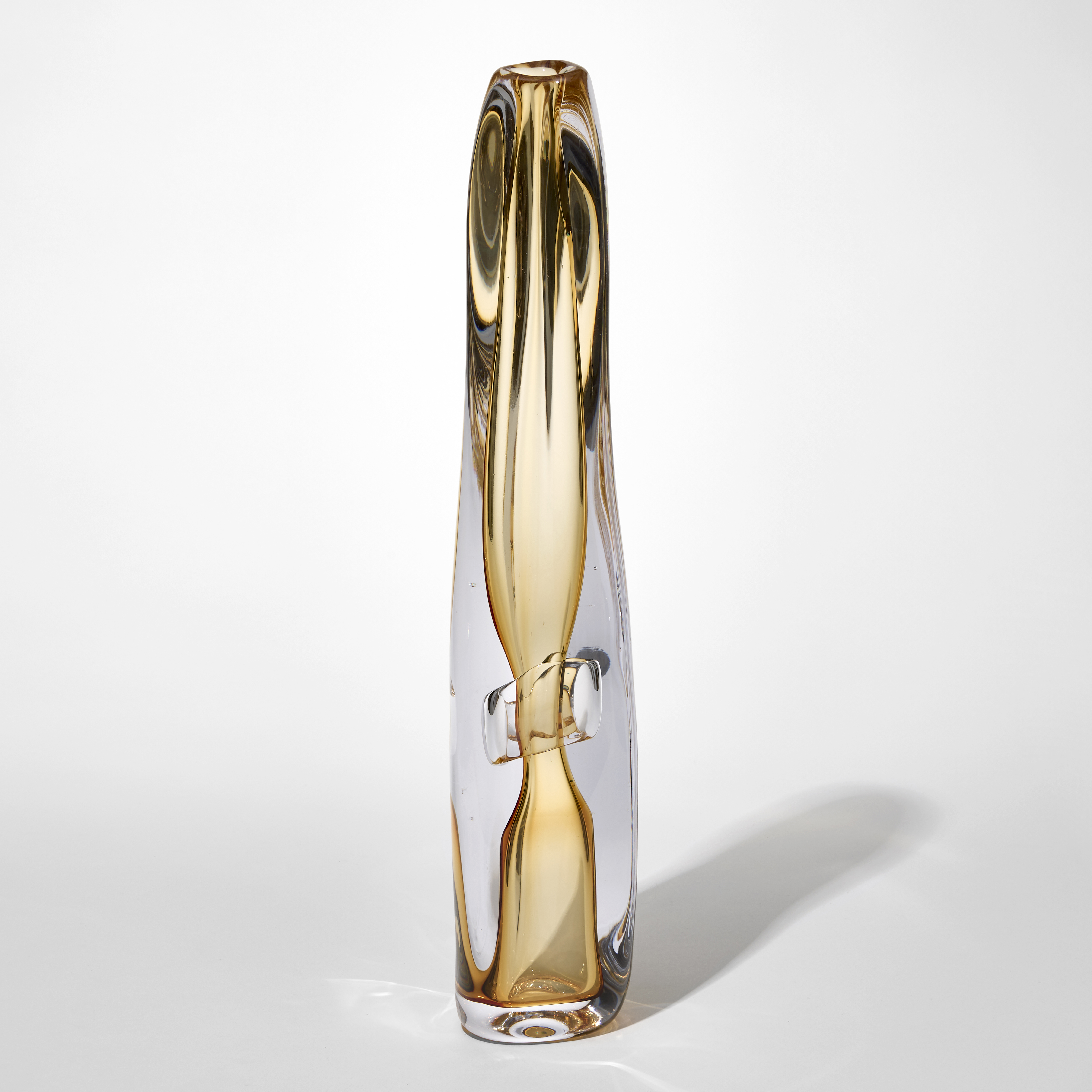 tall transparent fluid and slightly twisting vessel with small top opening and an outer later in clear and inner trapped undulating layer in light golden amber hand blown from glass