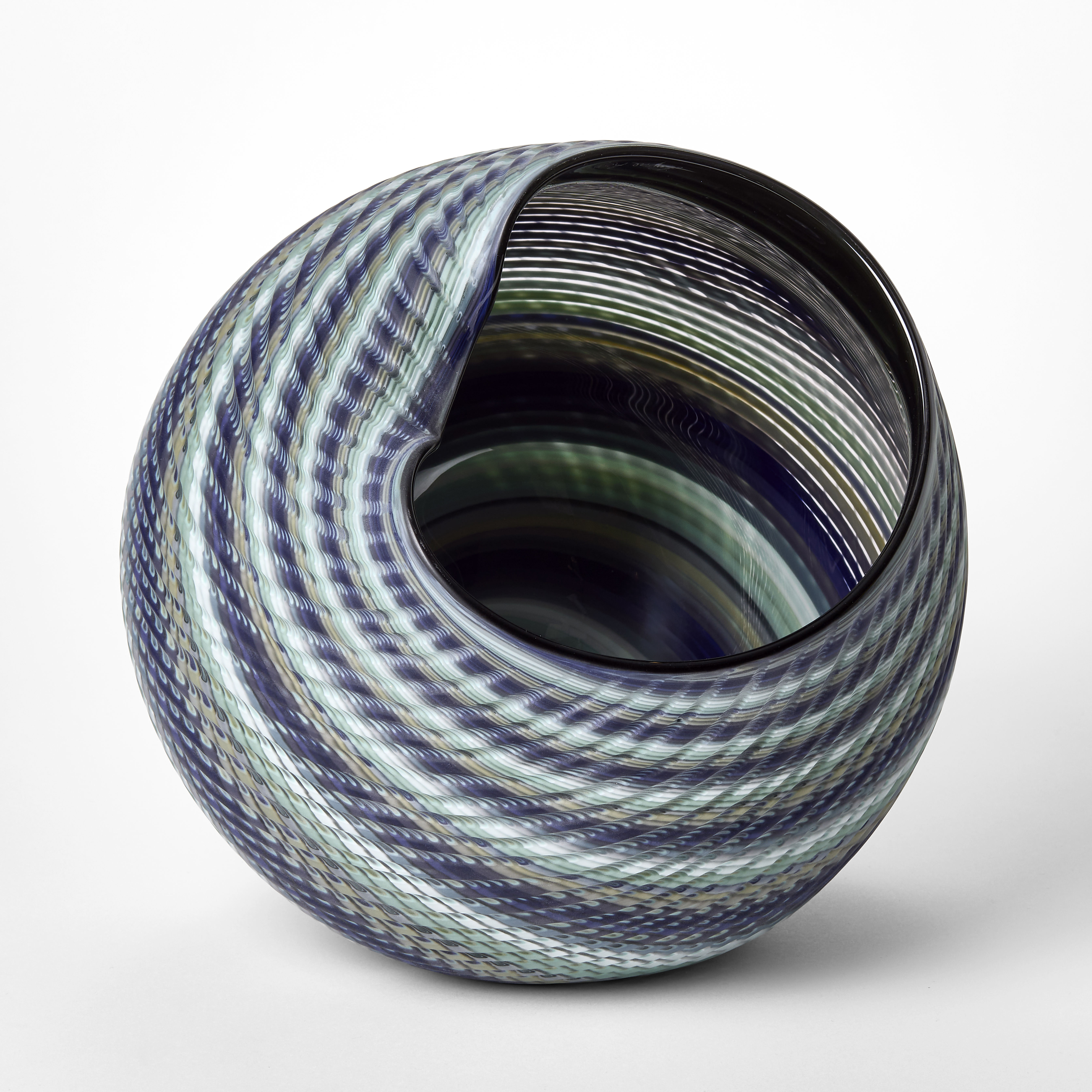 large round matt woven basket shaped vessel with wide offset opening created from banded canes in indigo jade blue celadon and soft grey hand blown and cut from glass